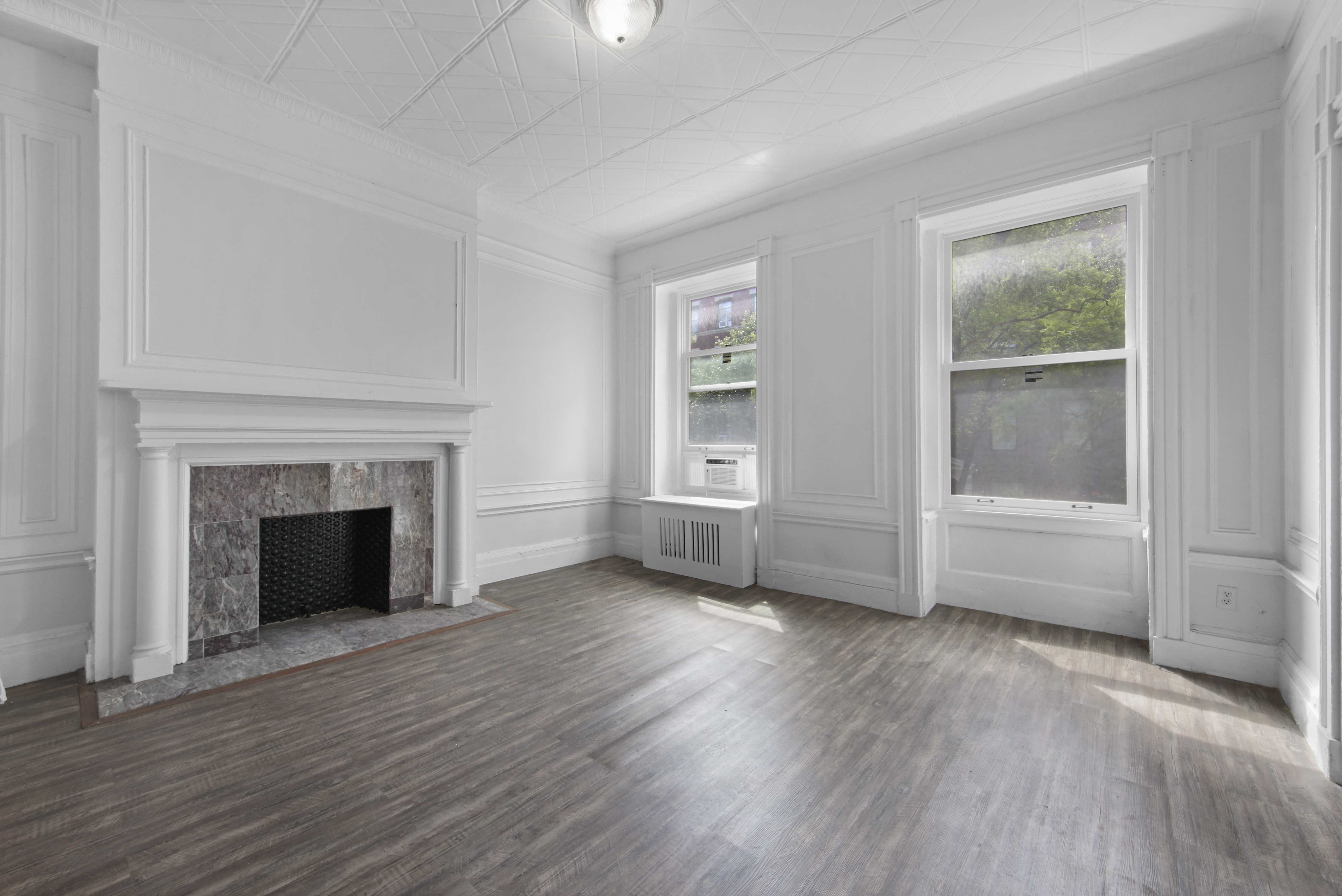 an empty room with wooden floor fireplace and windows