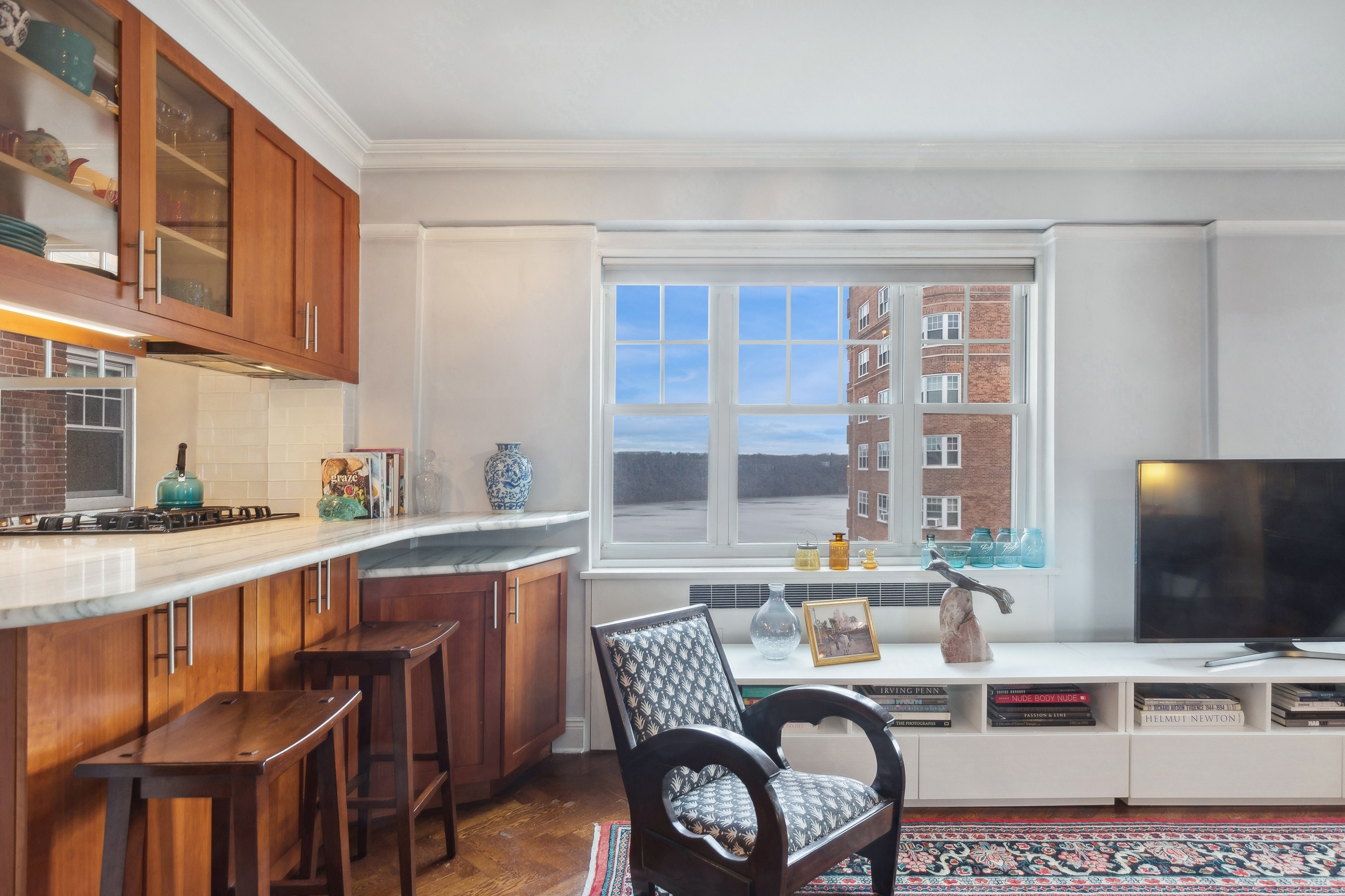 a living room with stainless steel appliances furniture a flat screen tv and kitchen view