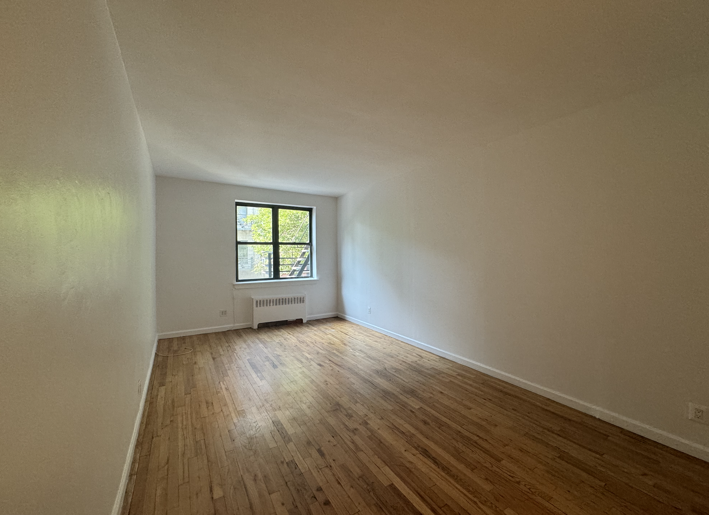 an empty room with wooden floor and window