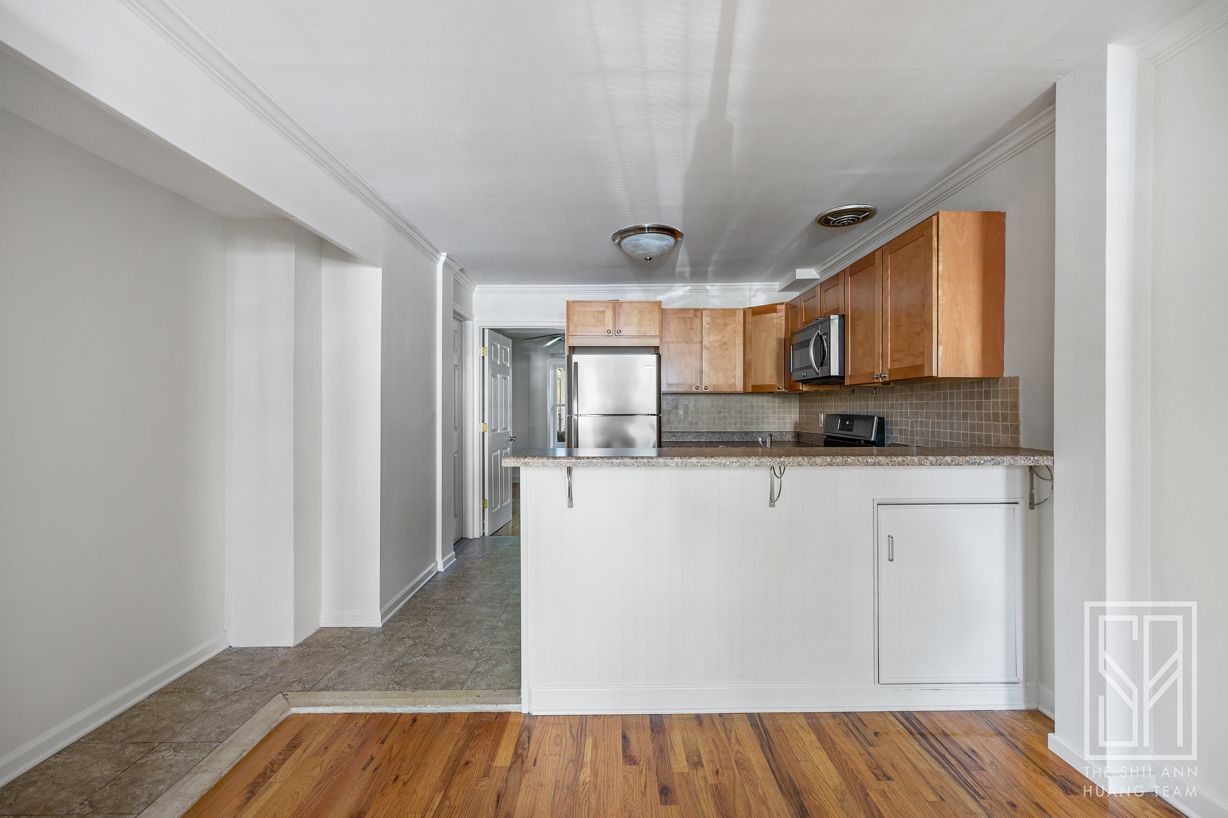 a living room with stainless steel appliances granite countertop furniture and a wooden floor