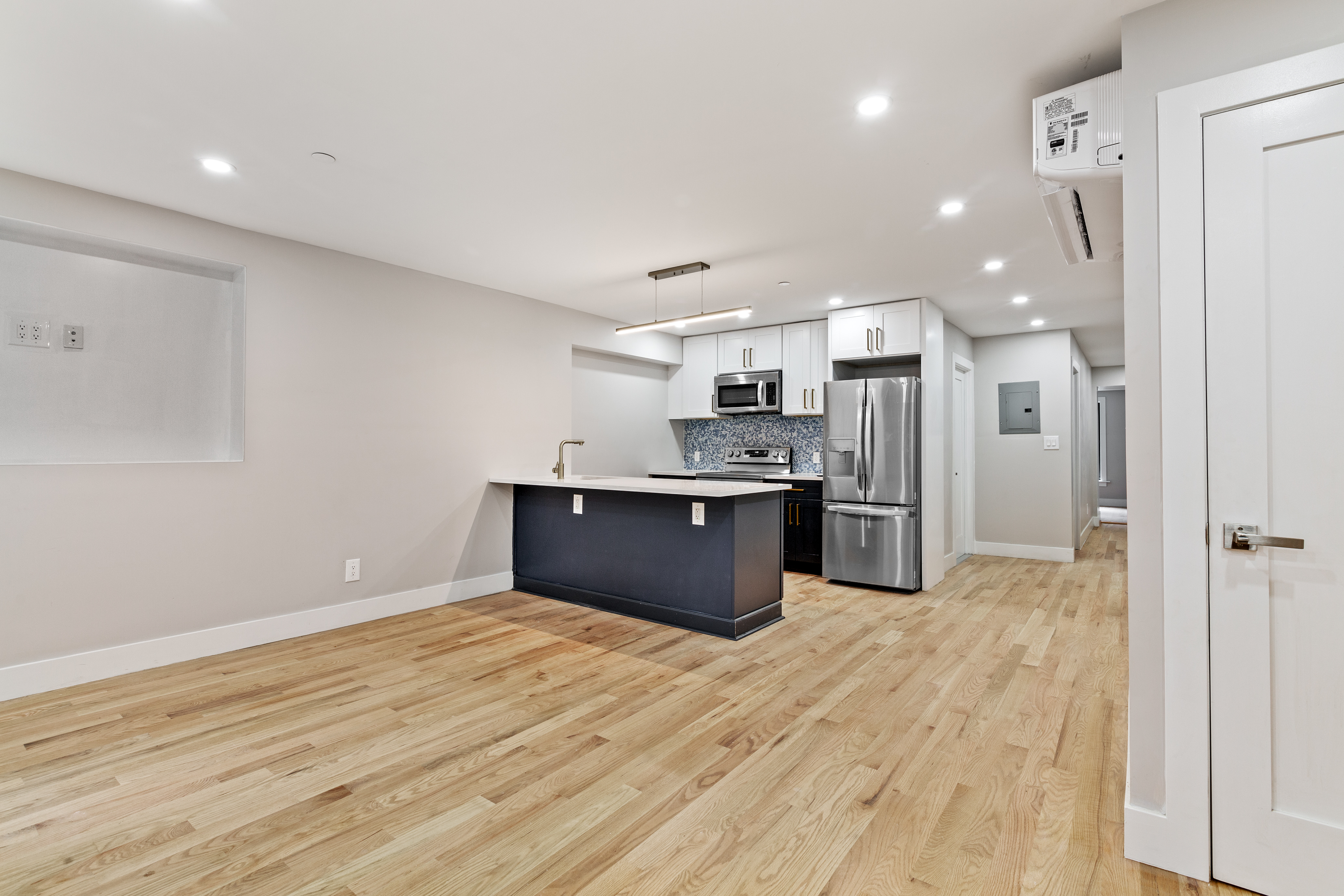 a large kitchen with stainless steel appliances kitchen island a large counter top and wooden floors