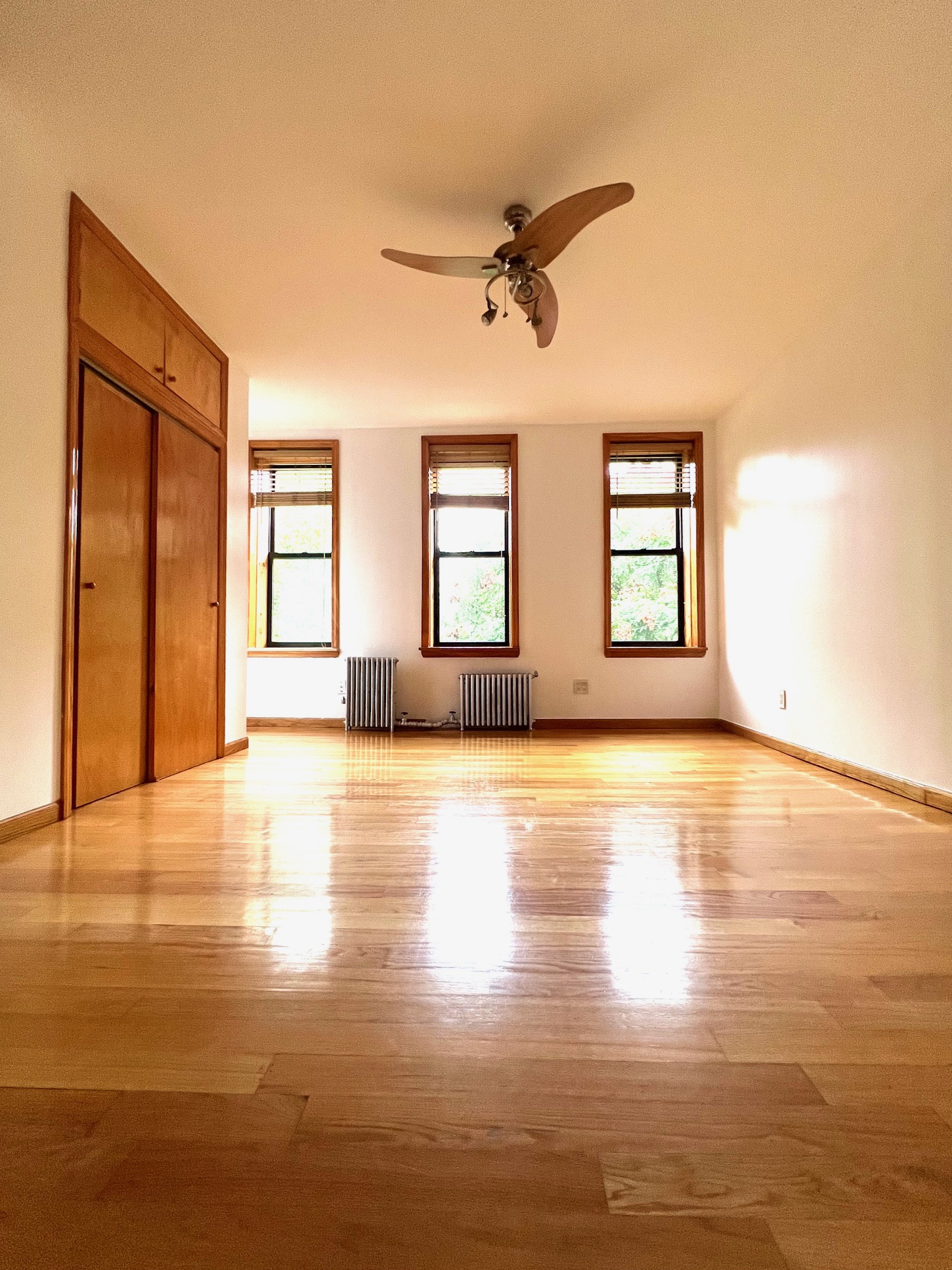 a view of an empty room with window and wooden floor