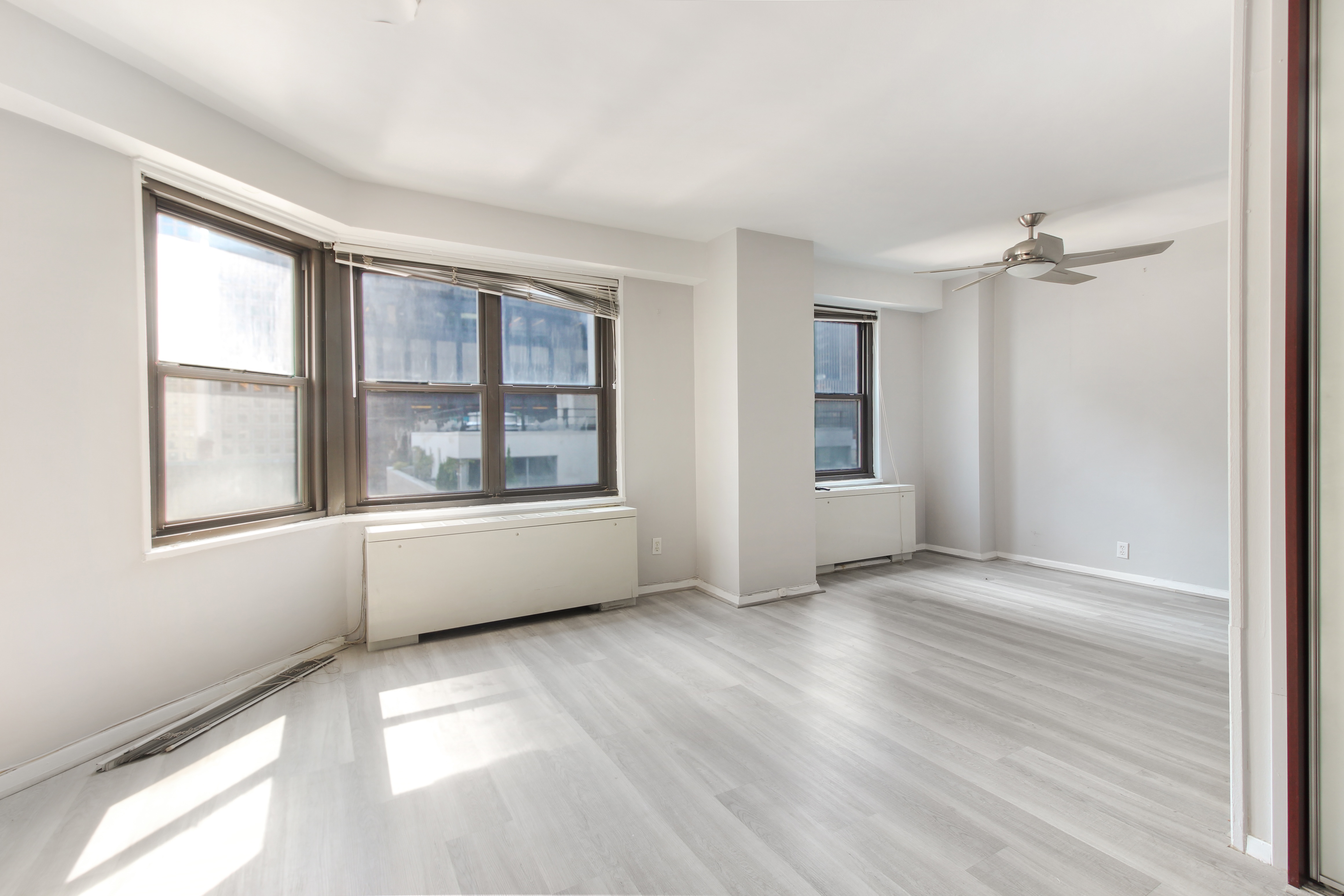 an empty room with wooden floor and windows