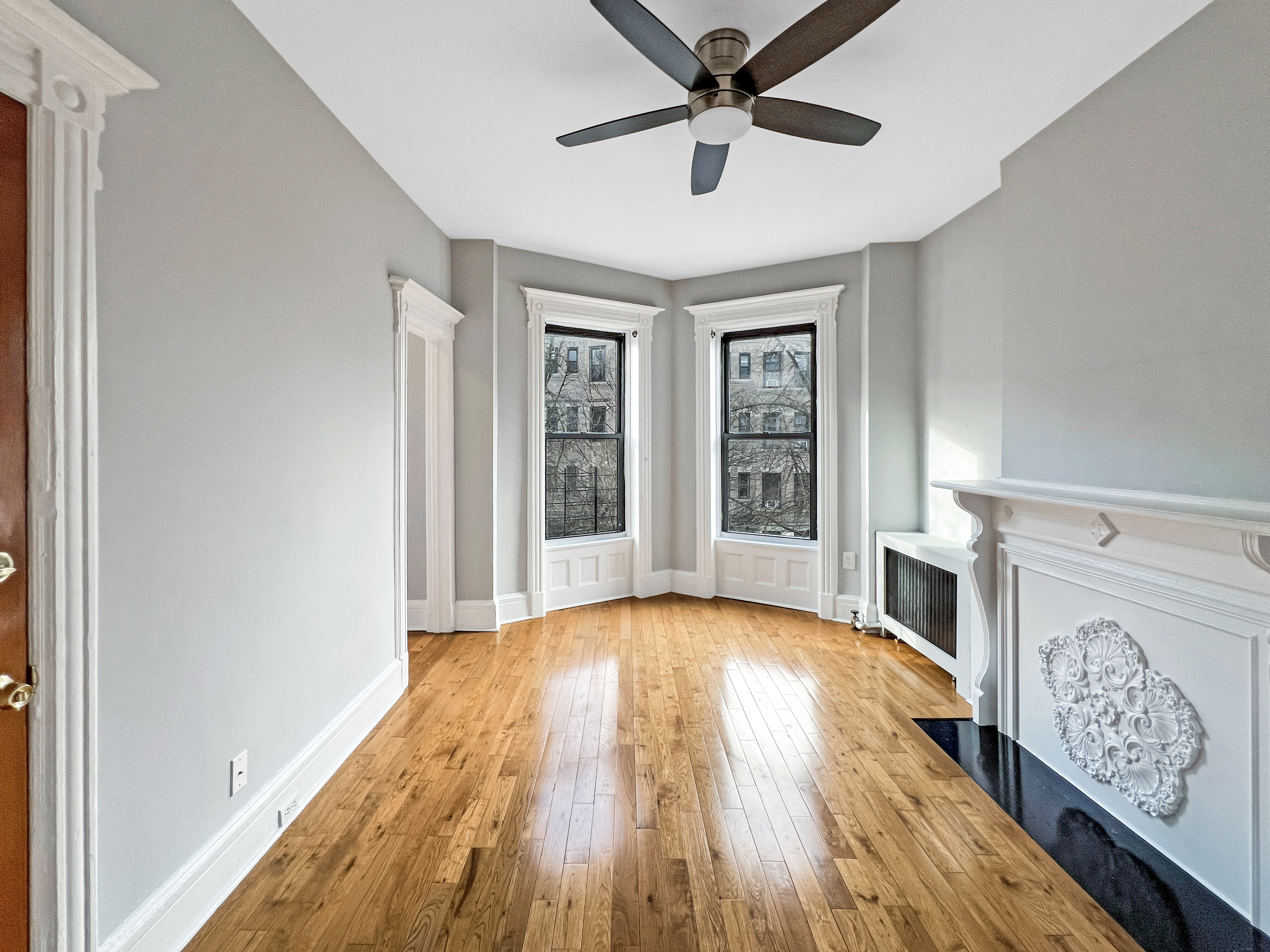 a view of an empty room with window and wooden floor