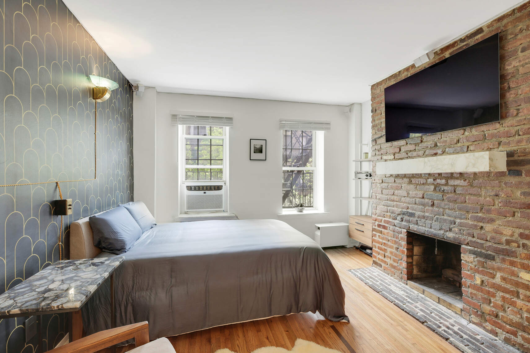 a bedroom with a bed a flat screen tv and a fireplace