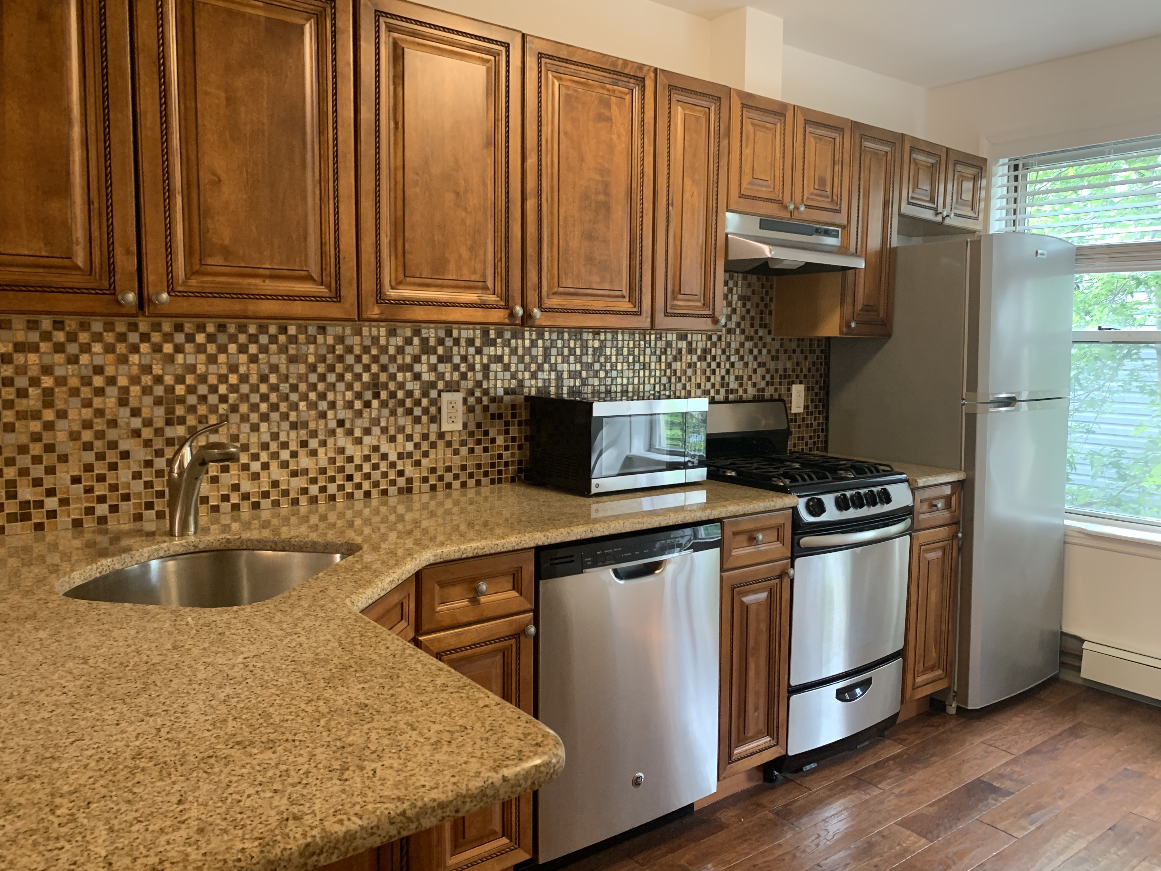 a kitchen with stainless steel appliances granite countertop a stove a refrigerator and a sink with wooden cabinets