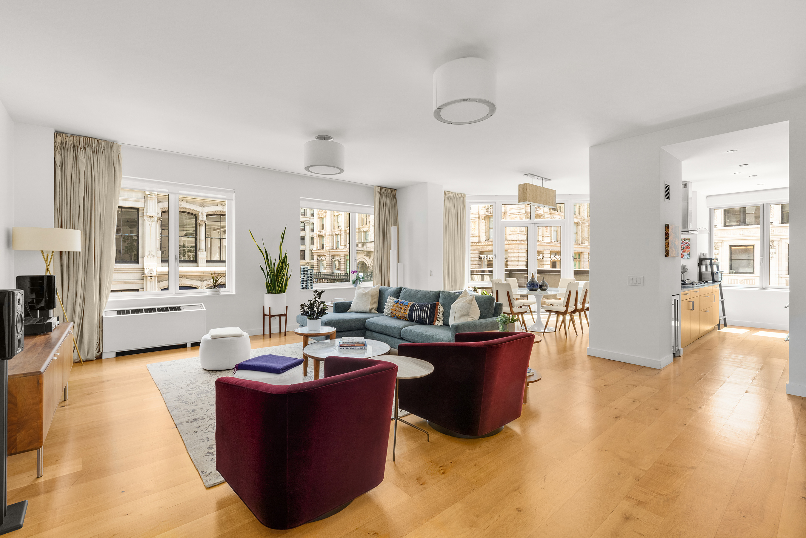 a living room with couches and kitchen view with wooden floor