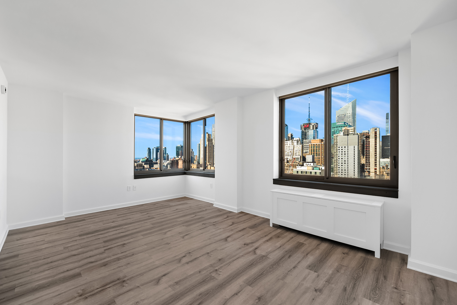 a view of an empty room with window and wooden floor