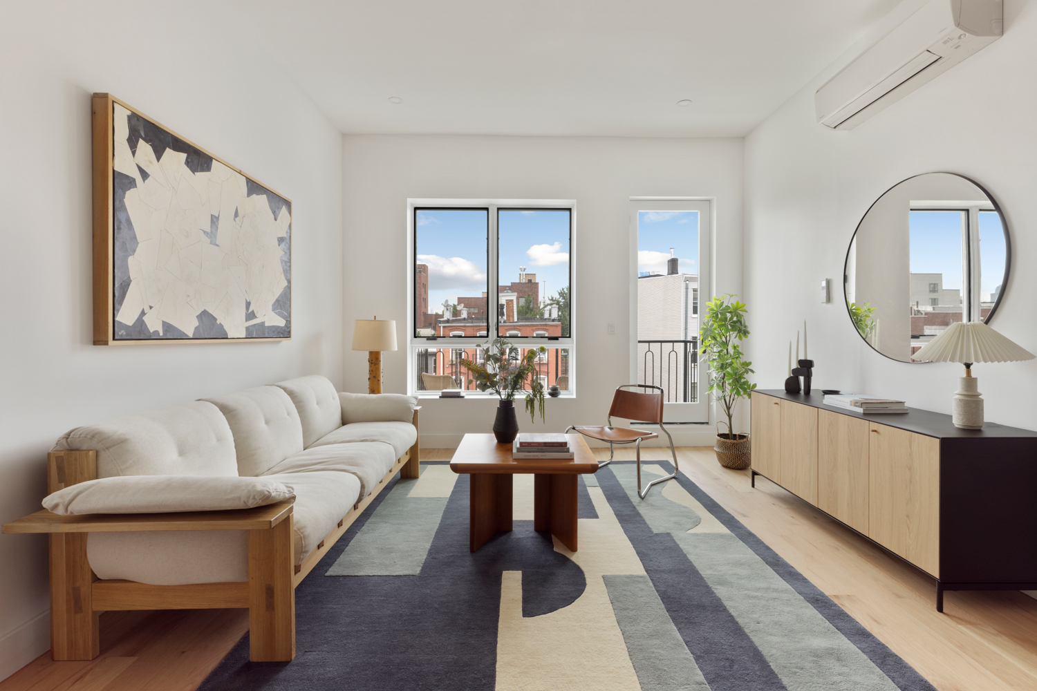 a living room with furniture a mirror and a wooden floor