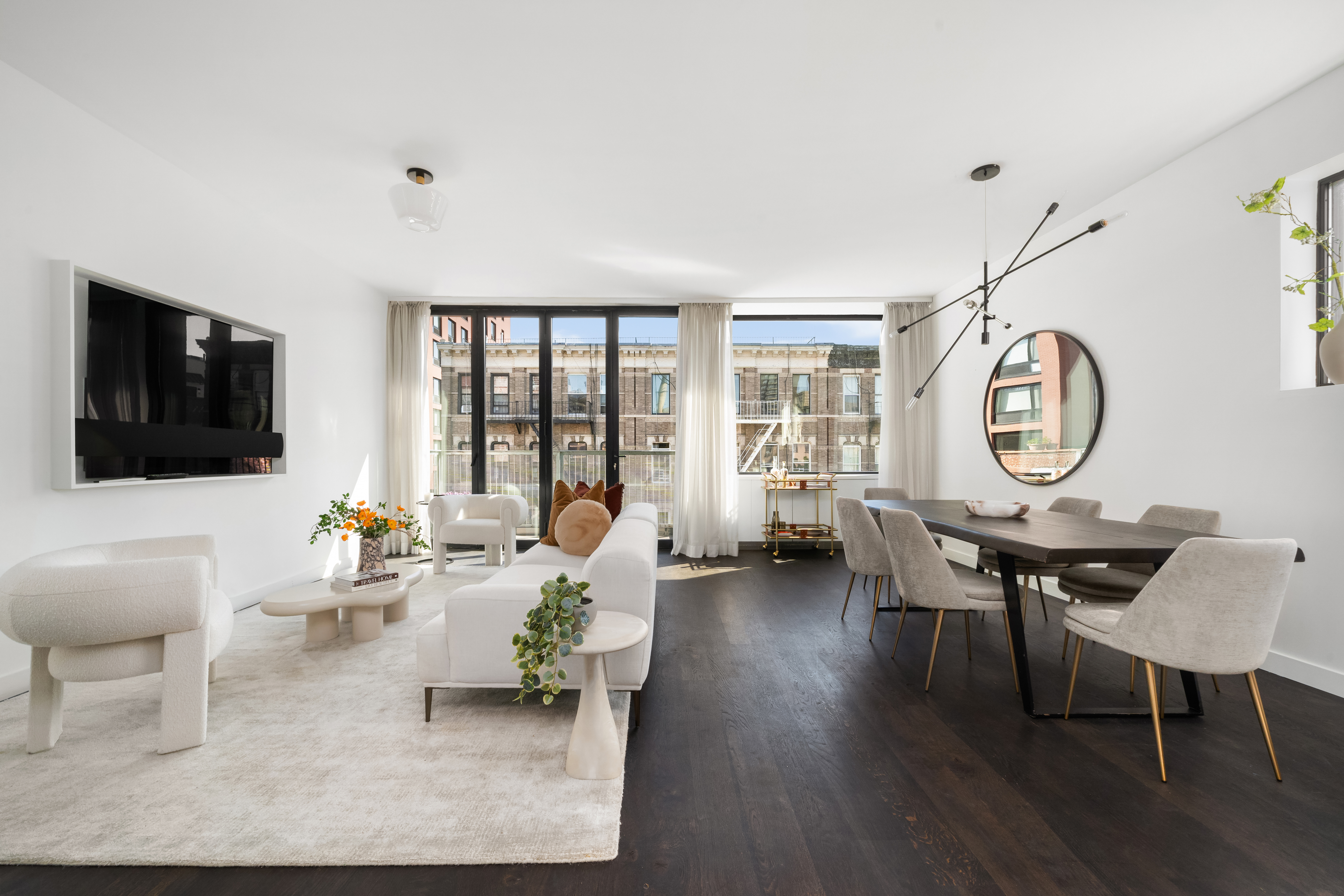 a living room with furniture a rug a flat screen tv and a large window