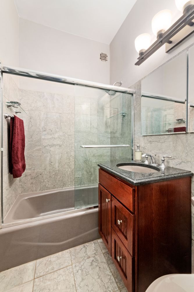 a bathroom with a granite countertop sink a mirror a bathtub and shower