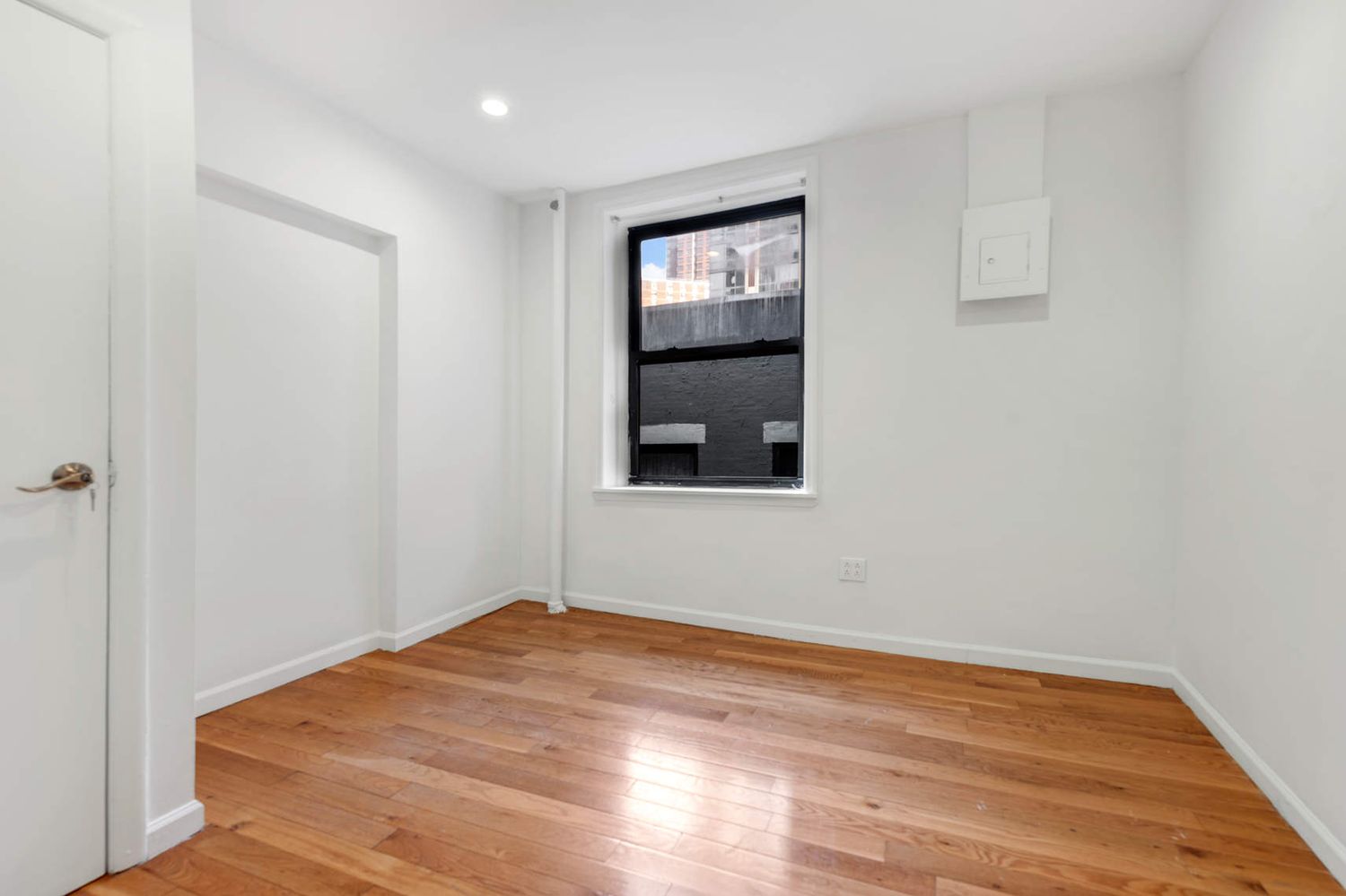 a view of empty room with wooden floor and fan