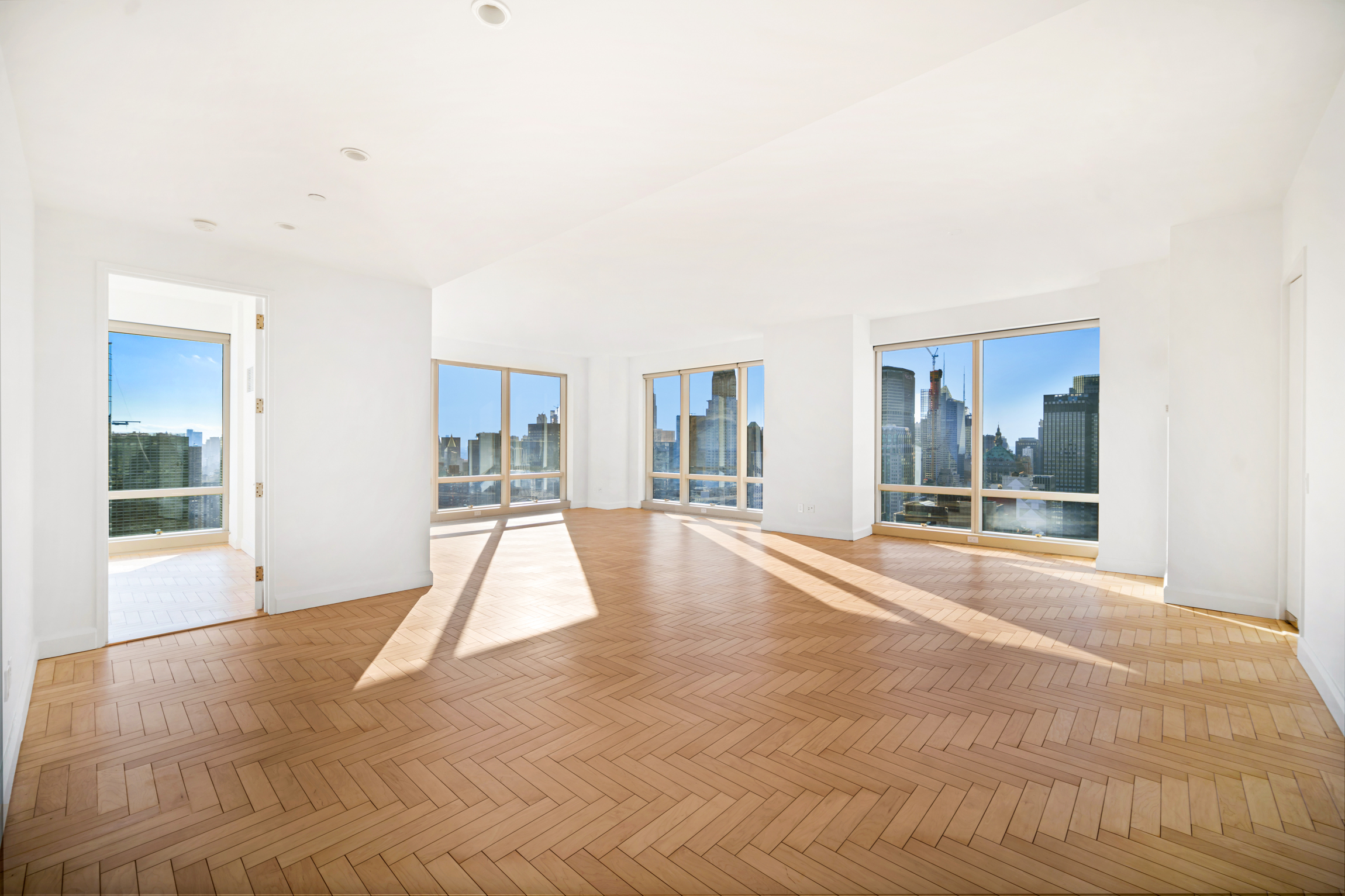 a view of an empty room with wooden floor and a large window