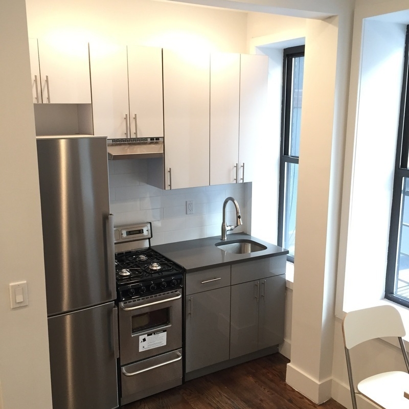 a kitchen with stainless steel appliances a refrigerator a sink and white cabinets