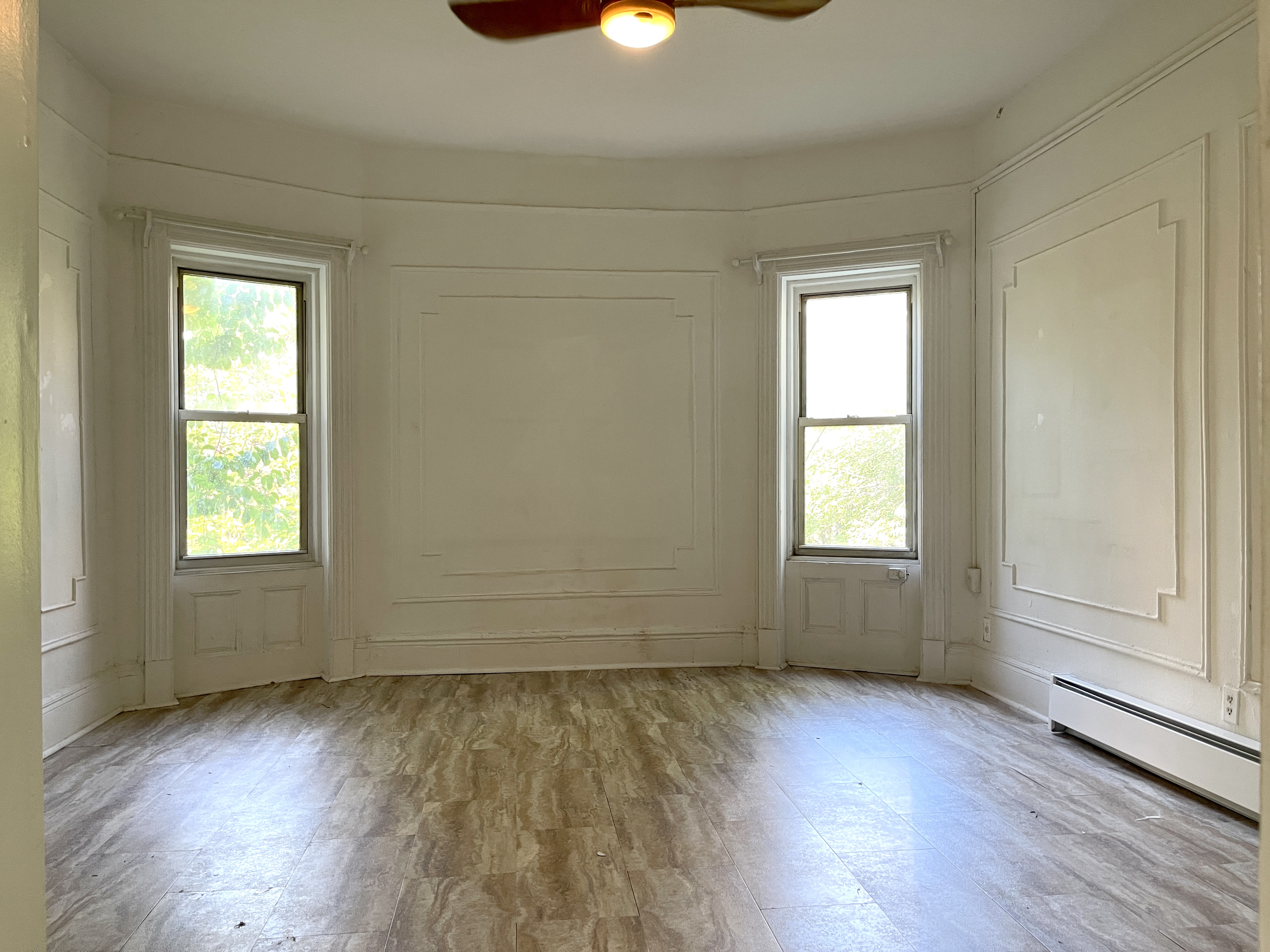 an empty room with wooden floor cabinet and windows