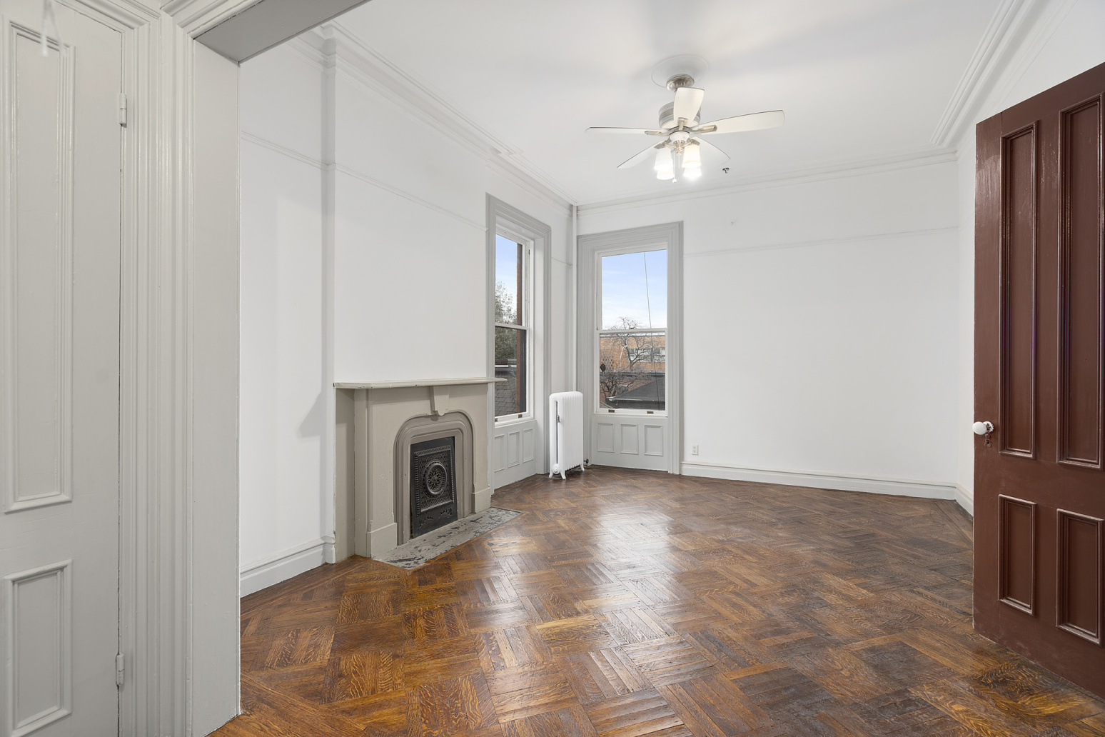 a view of a livingroom with a fireplace a ceiling fan and windows