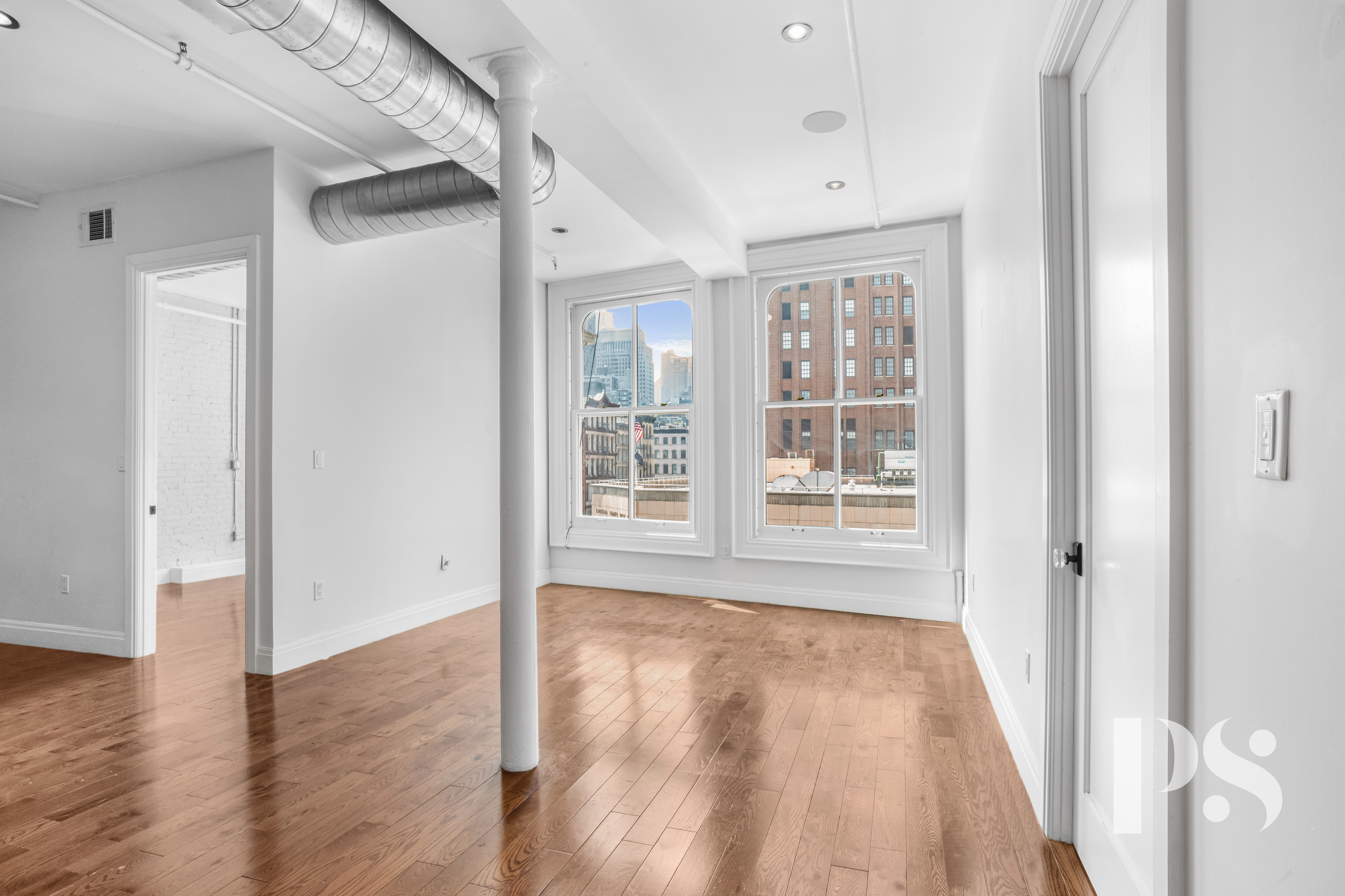 a view of an empty room with wooden floor and a window