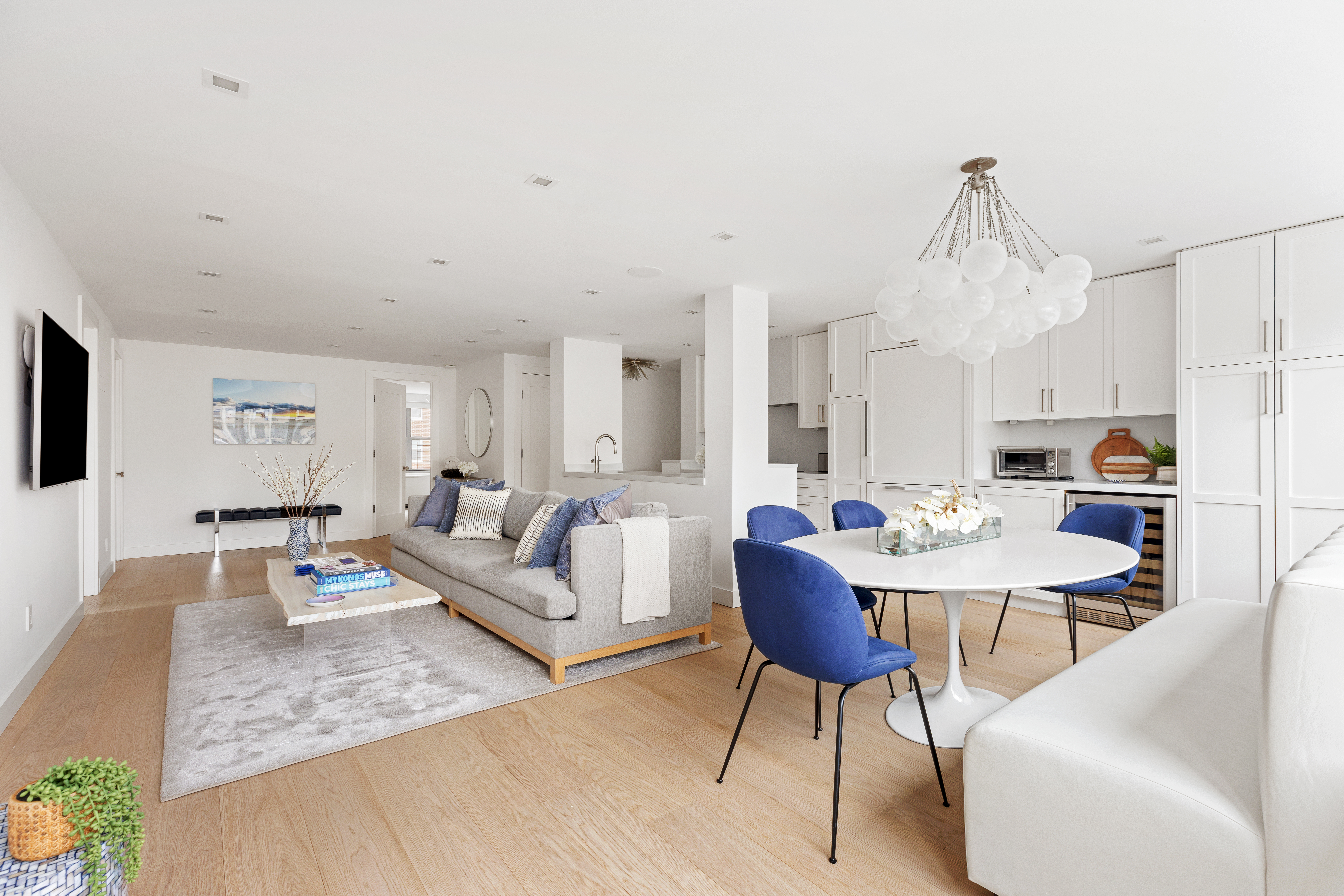 a living room with furniture kitchen view and a chandelier