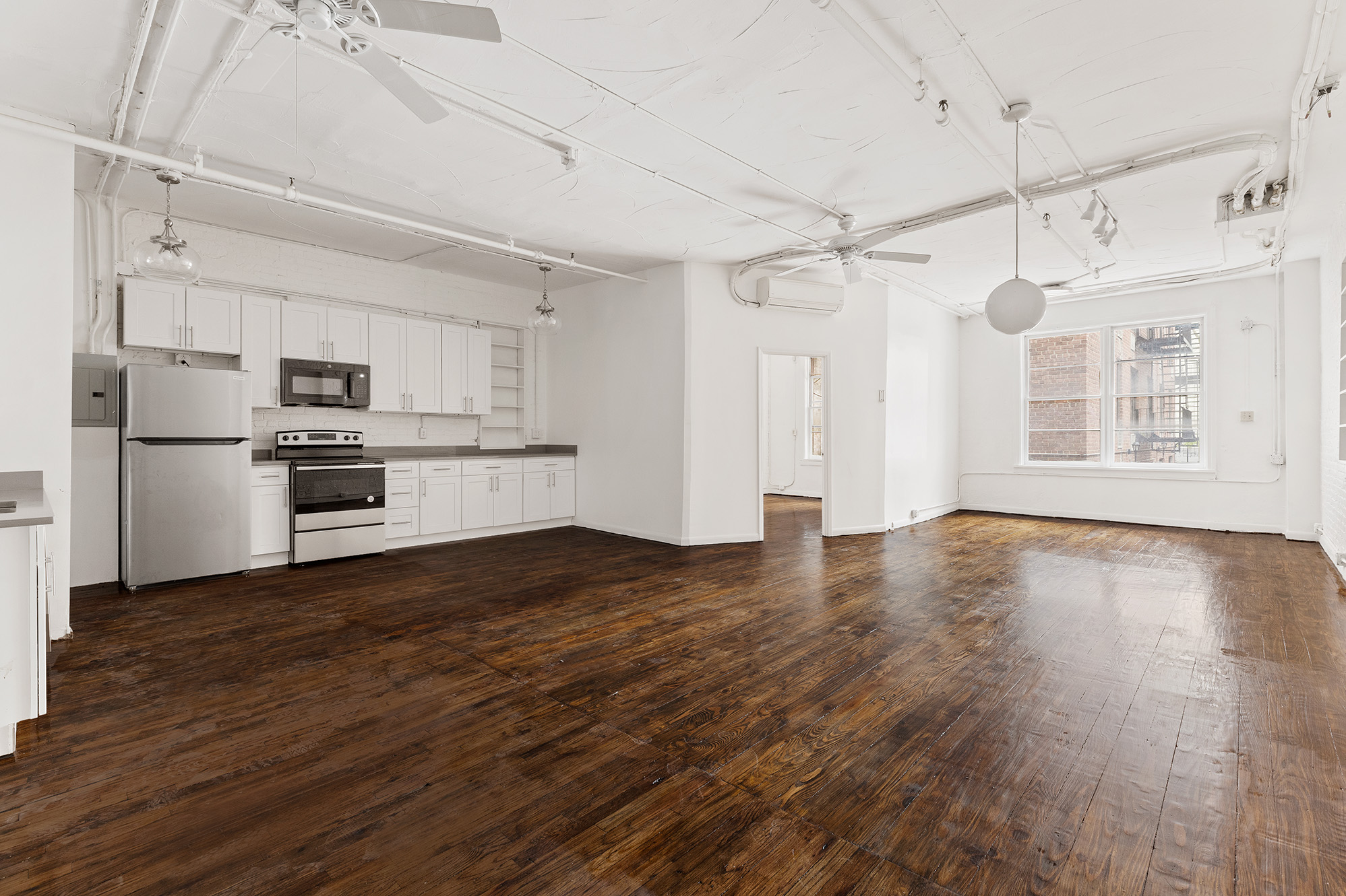 a view of a kitchen with a refrigerator a ceiling fan and wooden floor