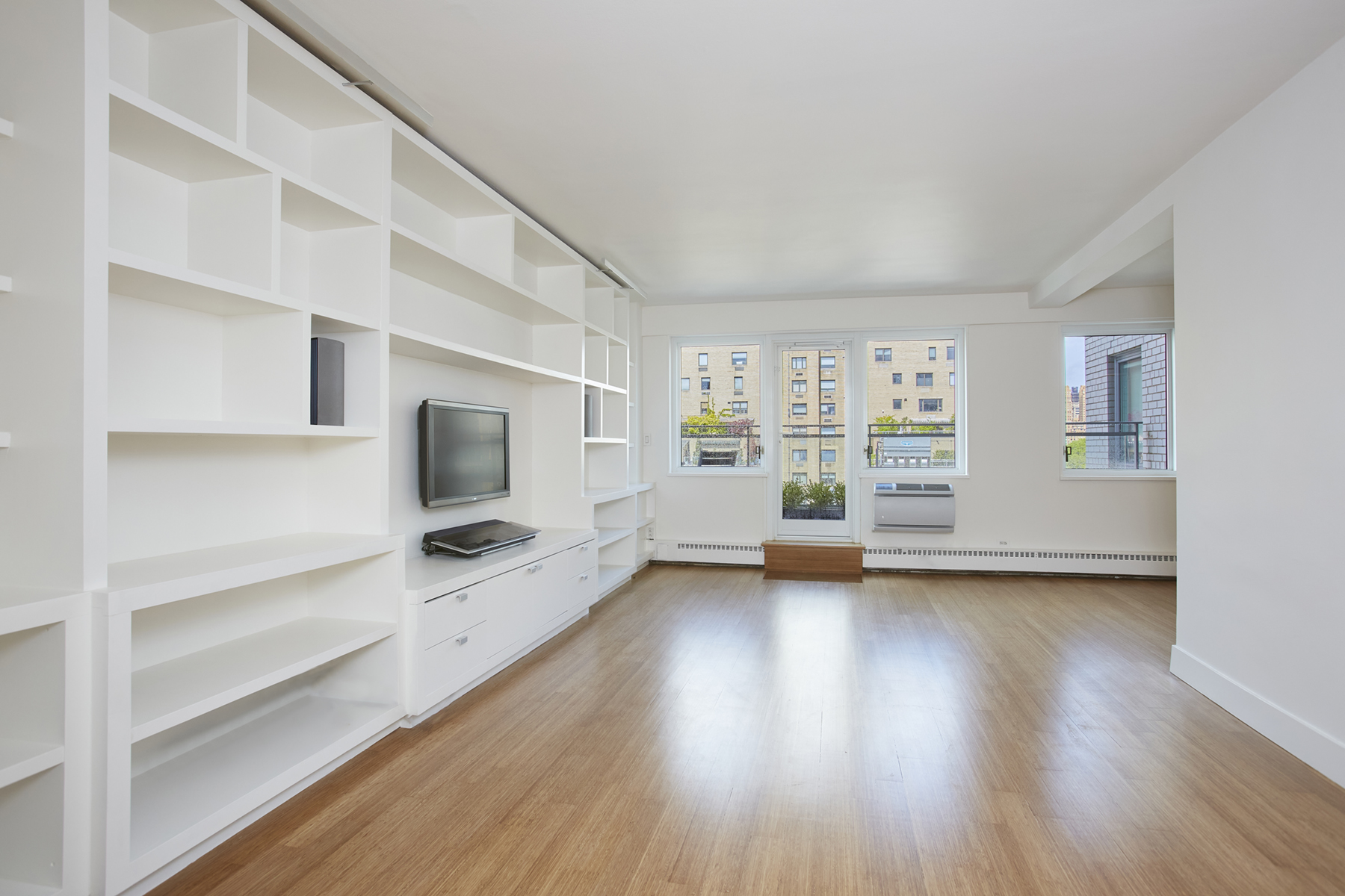 a view of an empty room with a window and wooden floor