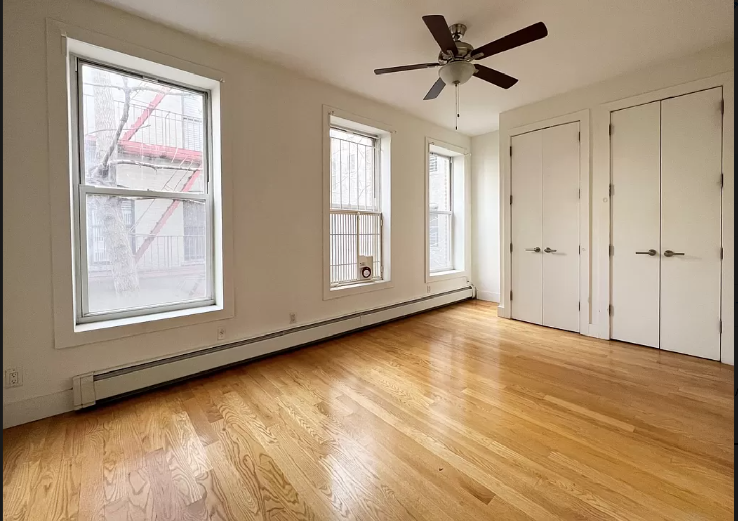 a view of an empty room with a window and wooden floor