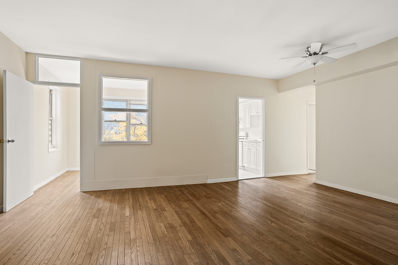 a view of an empty room with wooden floor and a window