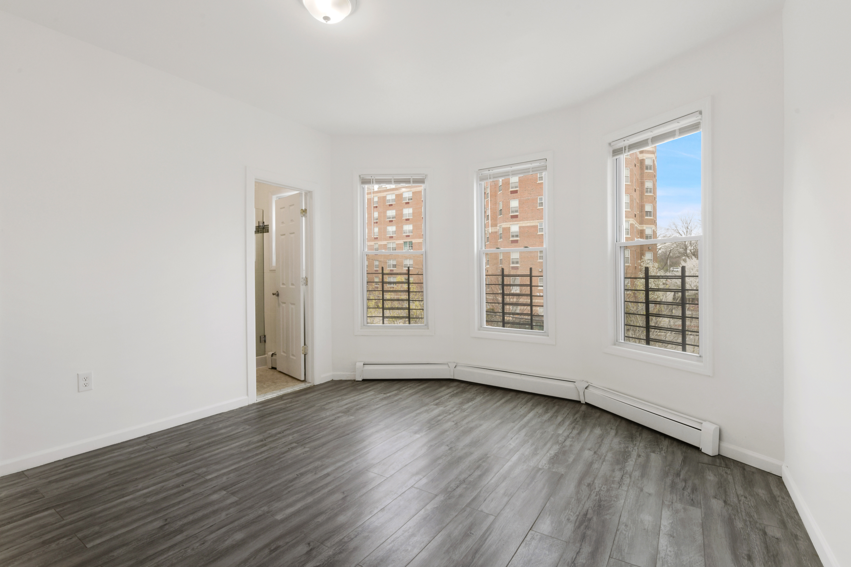 an empty room with wooden floor and windows