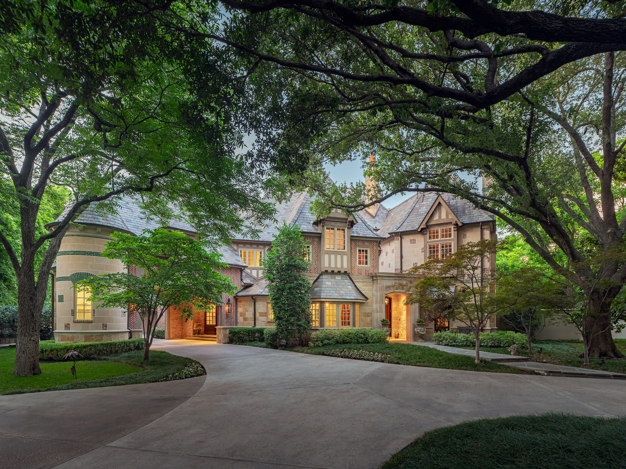 a view of a white house next to a yard with big trees