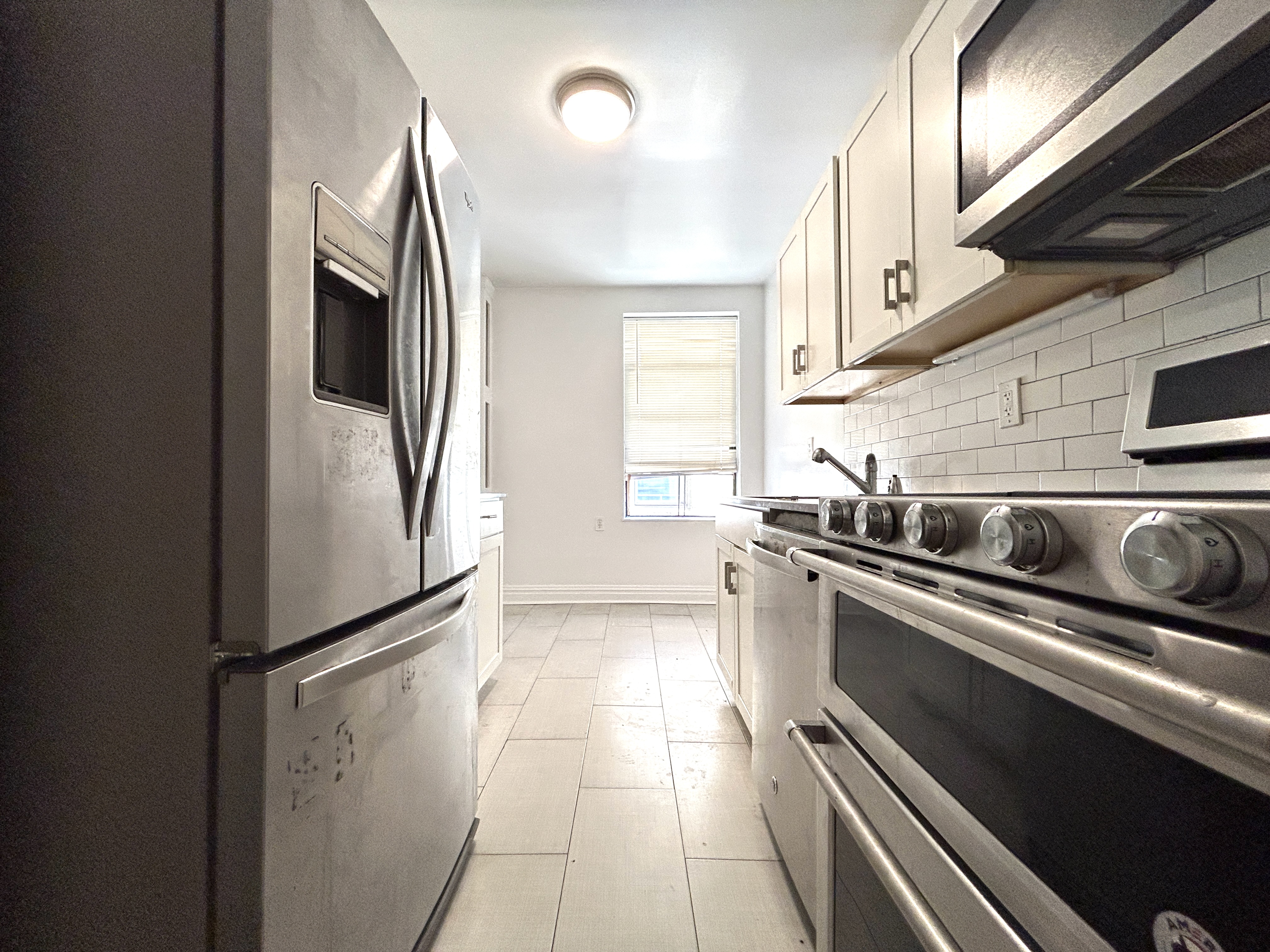 a kitchen with stainless steel appliances granite countertop a refrigerator a sink and white cabinets