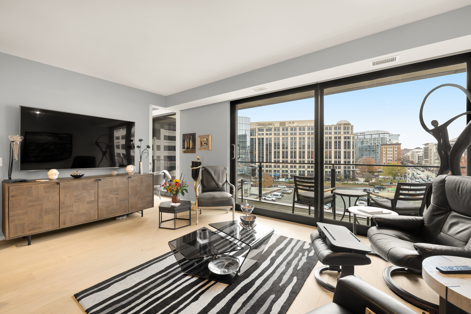 a living room with furniture a flat screen tv and a floor to ceiling window