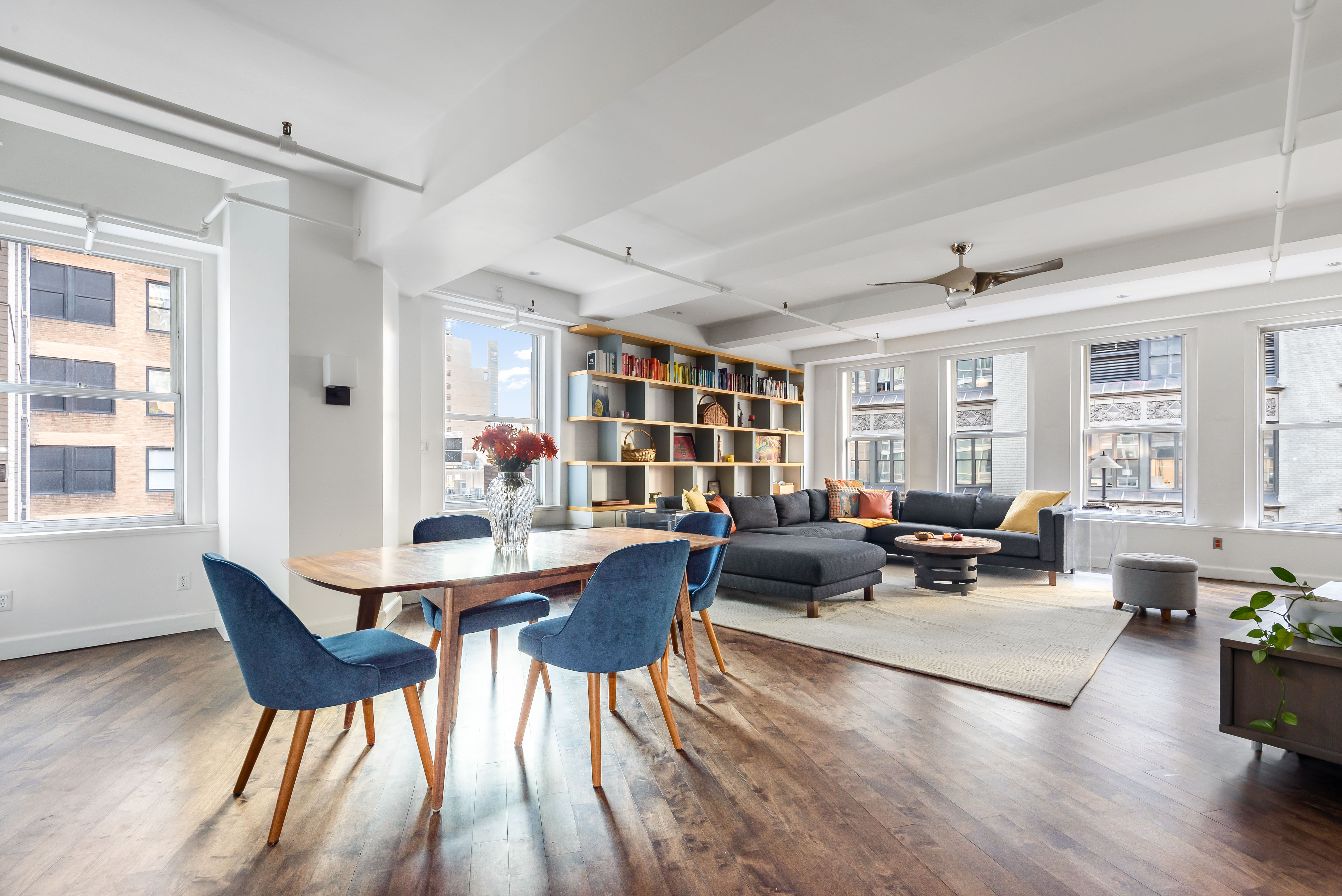 a living room with furniture two window and wooden floor