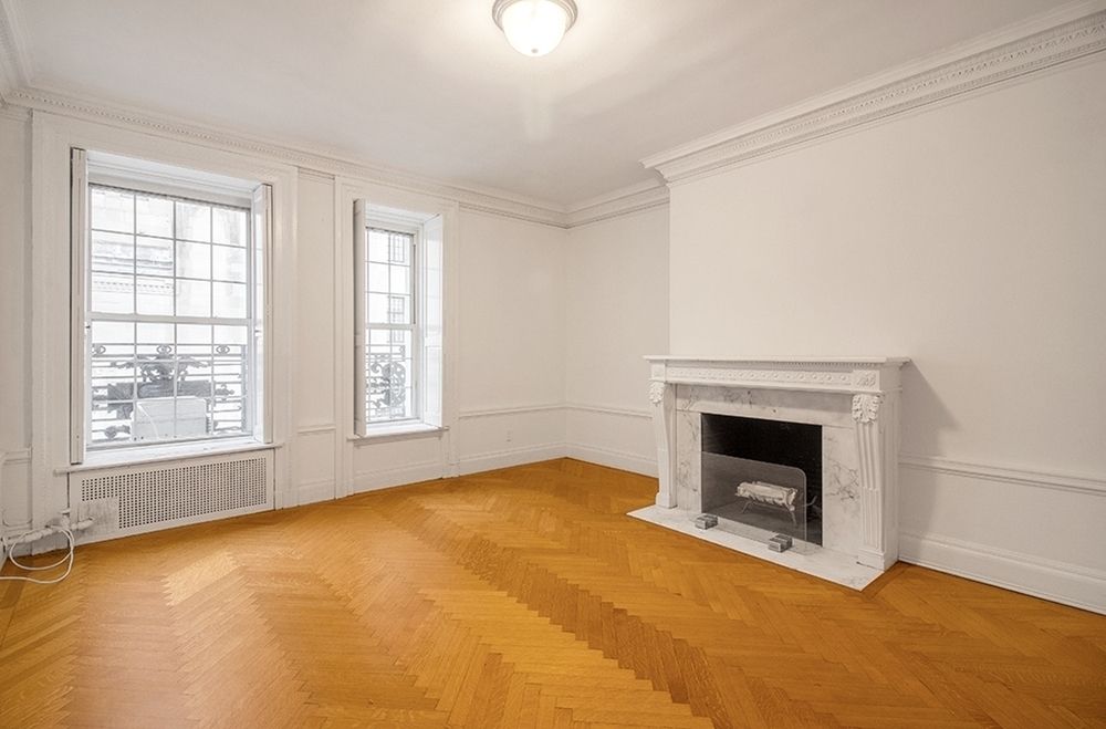 an empty room with windows and fireplace