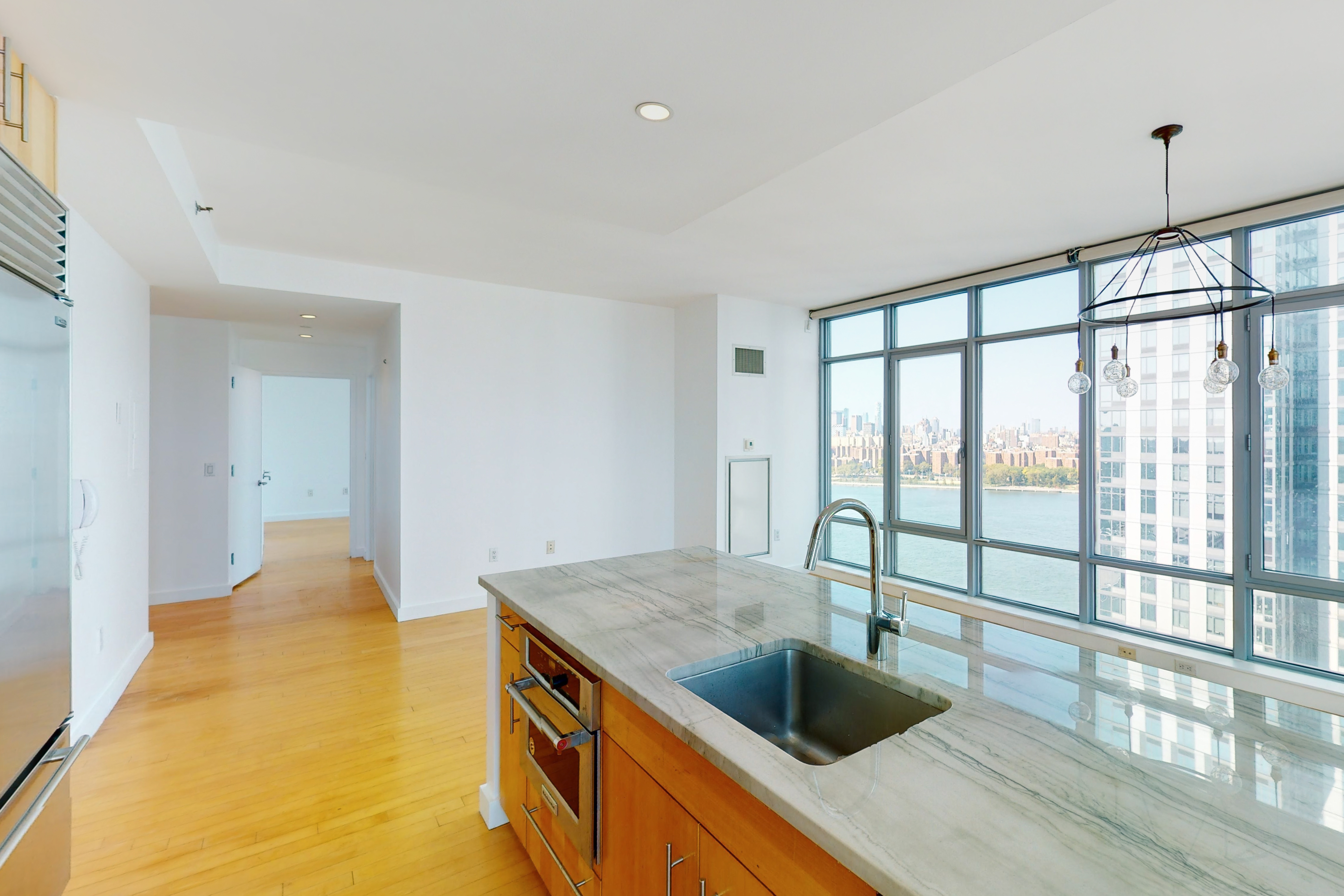 a view of a kitchen counter top a stove and wooden floor