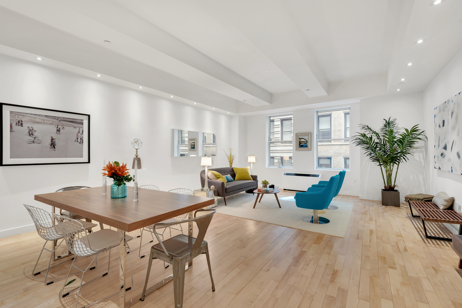 a living room with furniture a potted plant and open kitchen view