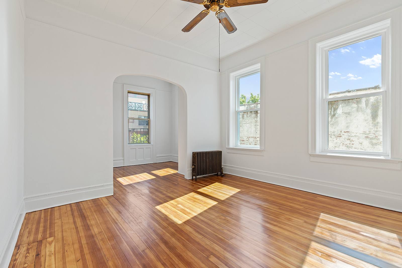 a view of empty room with wooden floor and fan