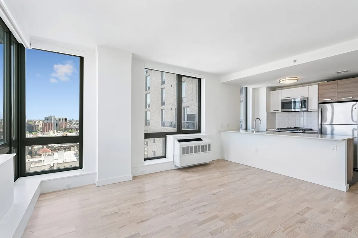 a large white kitchen with stainless steel appliances a large window and a counter top space