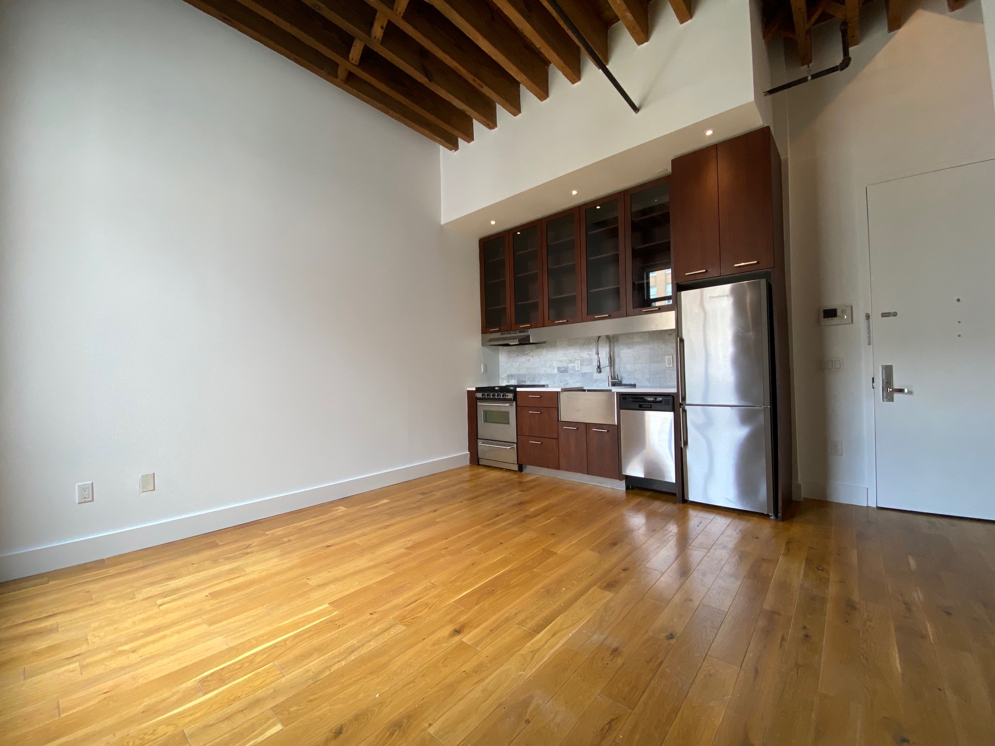 a view of kitchen with stainless steel appliances wooden floor and chair