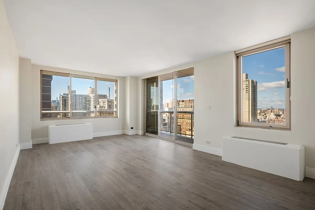 a view of a big room with wooden floor and a window