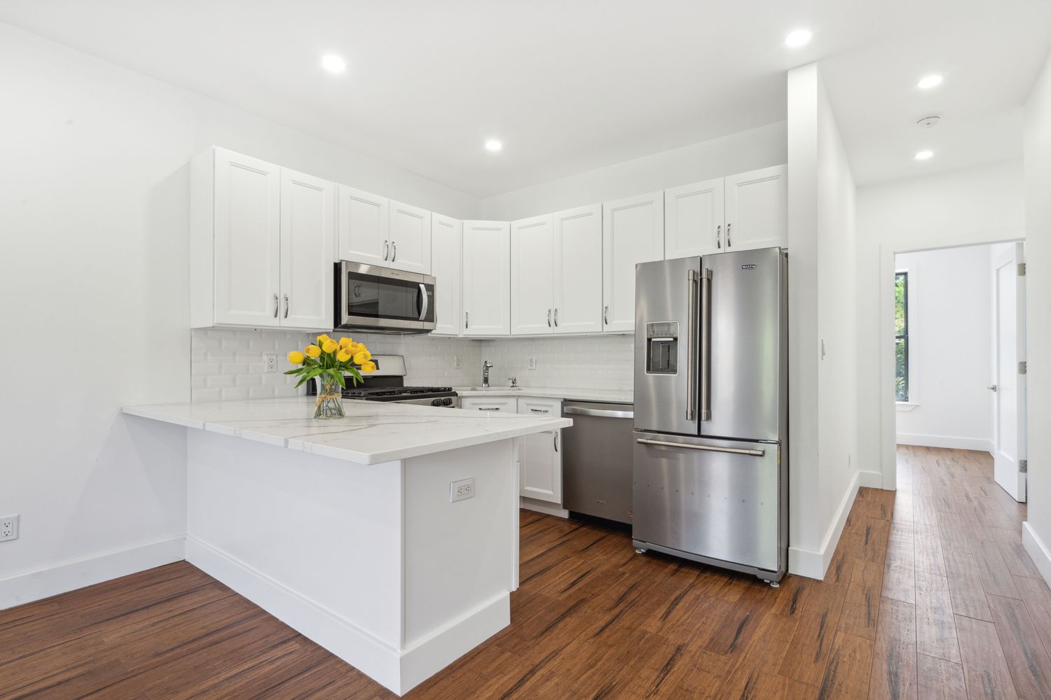 a kitchen with a refrigerator a stove cabinets and wooden floor