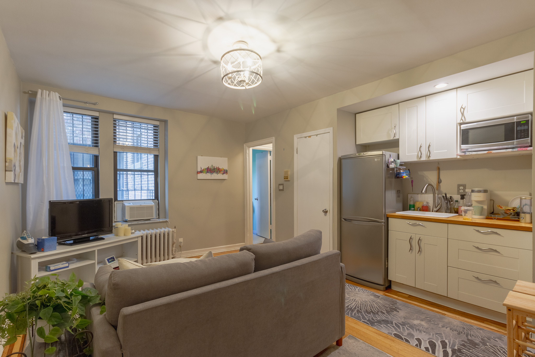 a living room with furniture a flat screen tv and a refrigerator