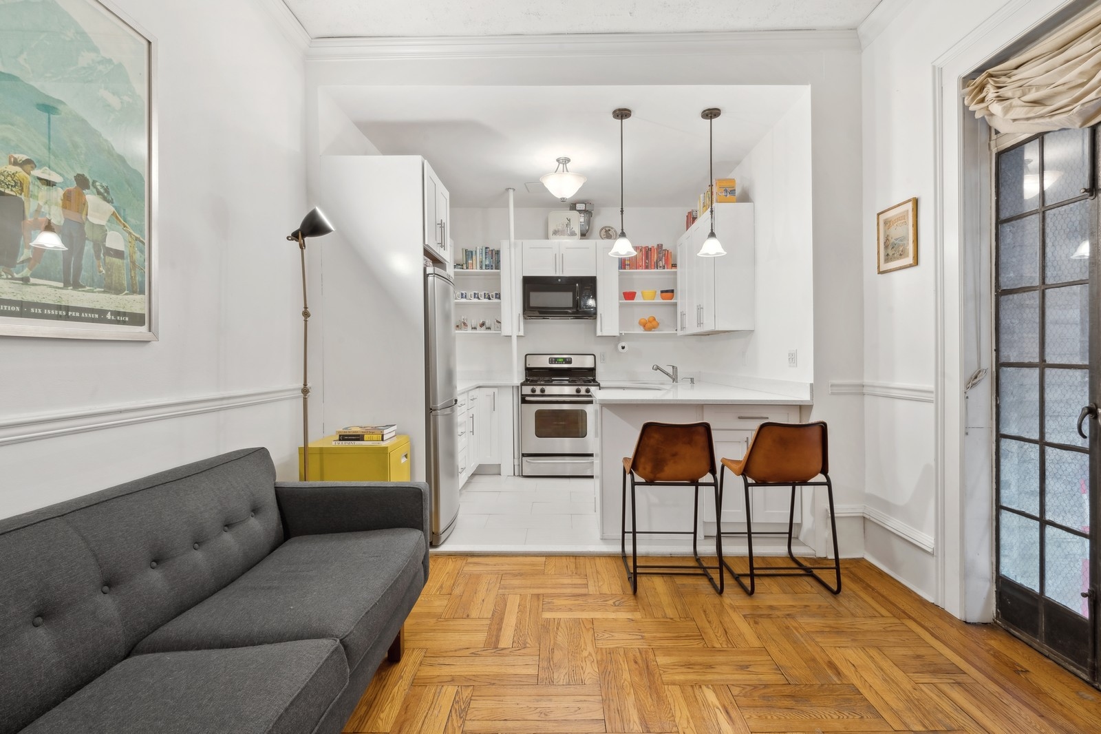 a living room with stainless steel appliances furniture and a kitchen view