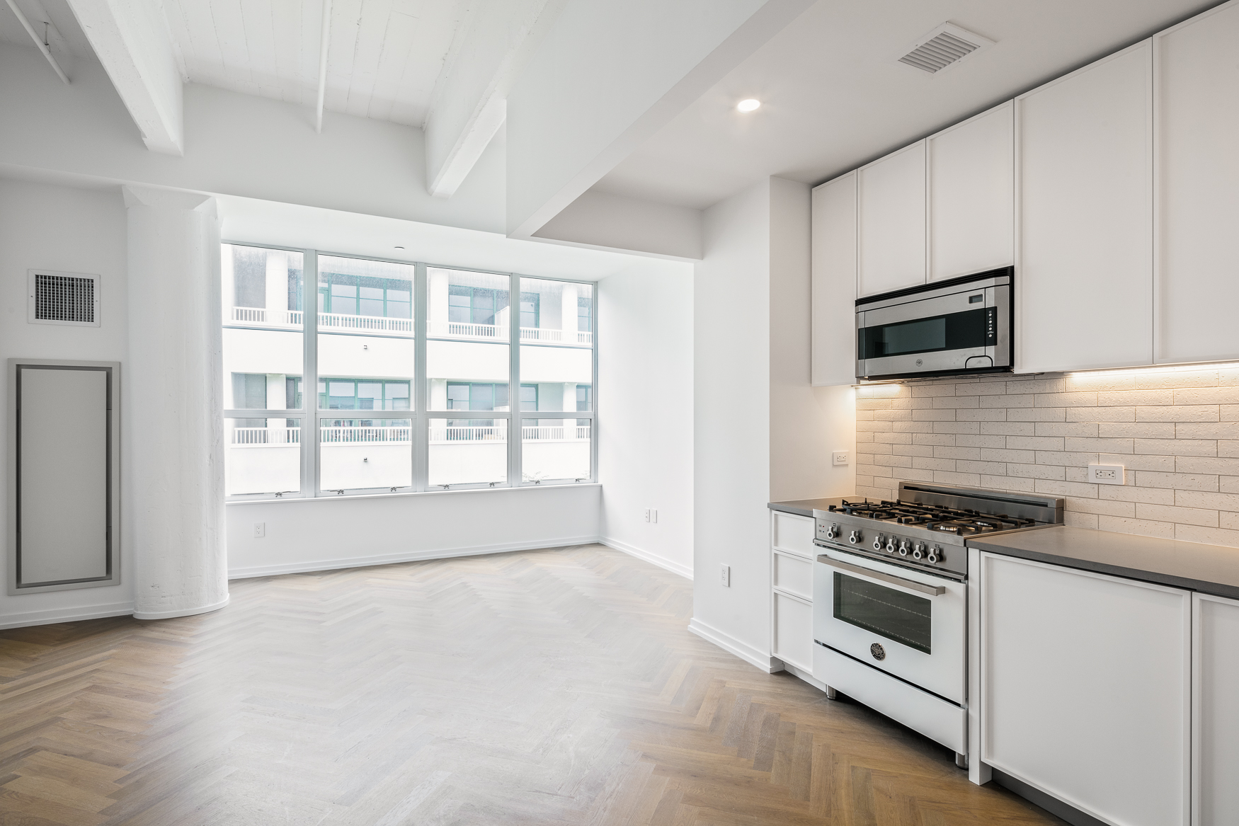 a kitchen with stainless steel appliances a stove a microwave and white cabinets