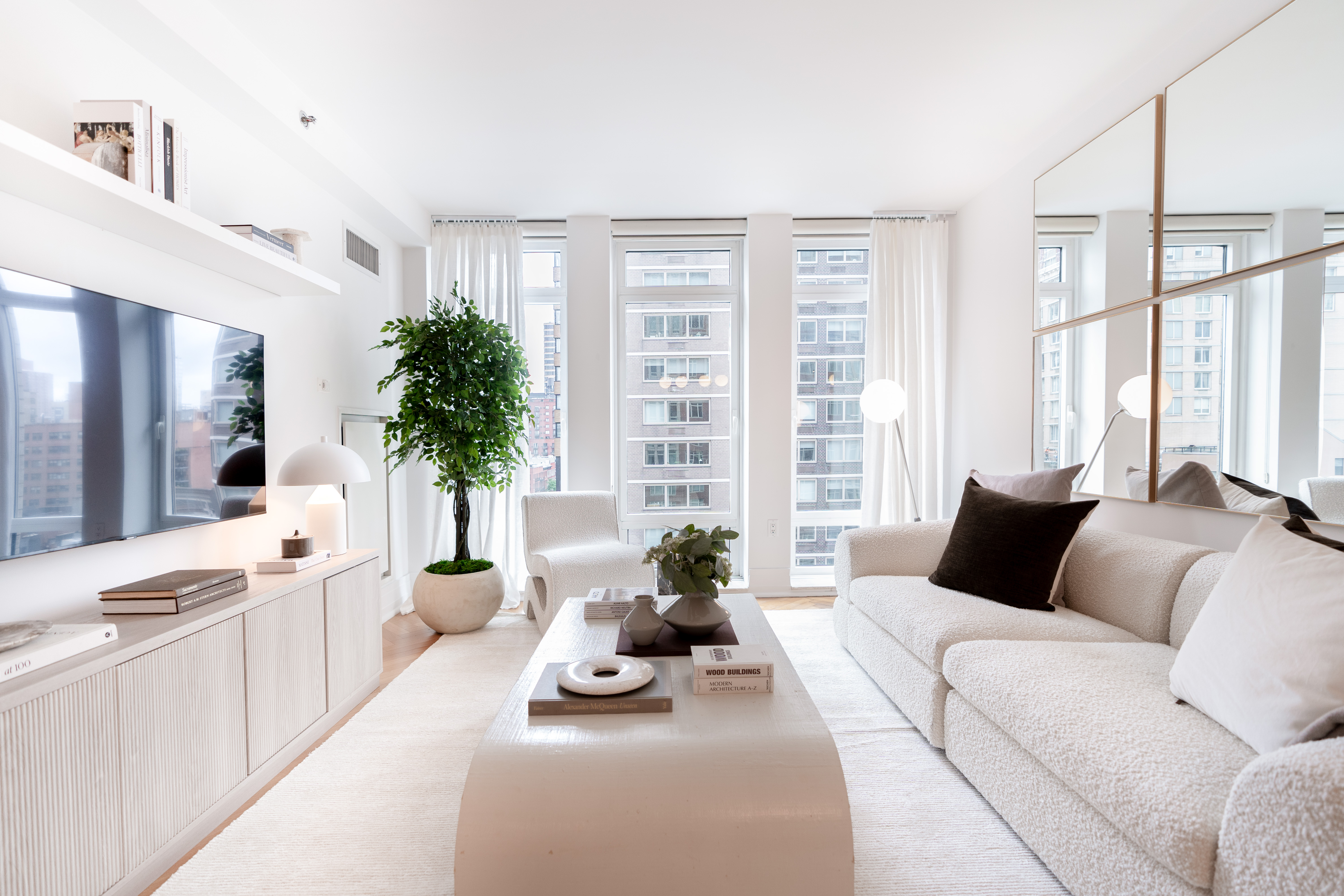 a living room with furniture large windows and a potted plant