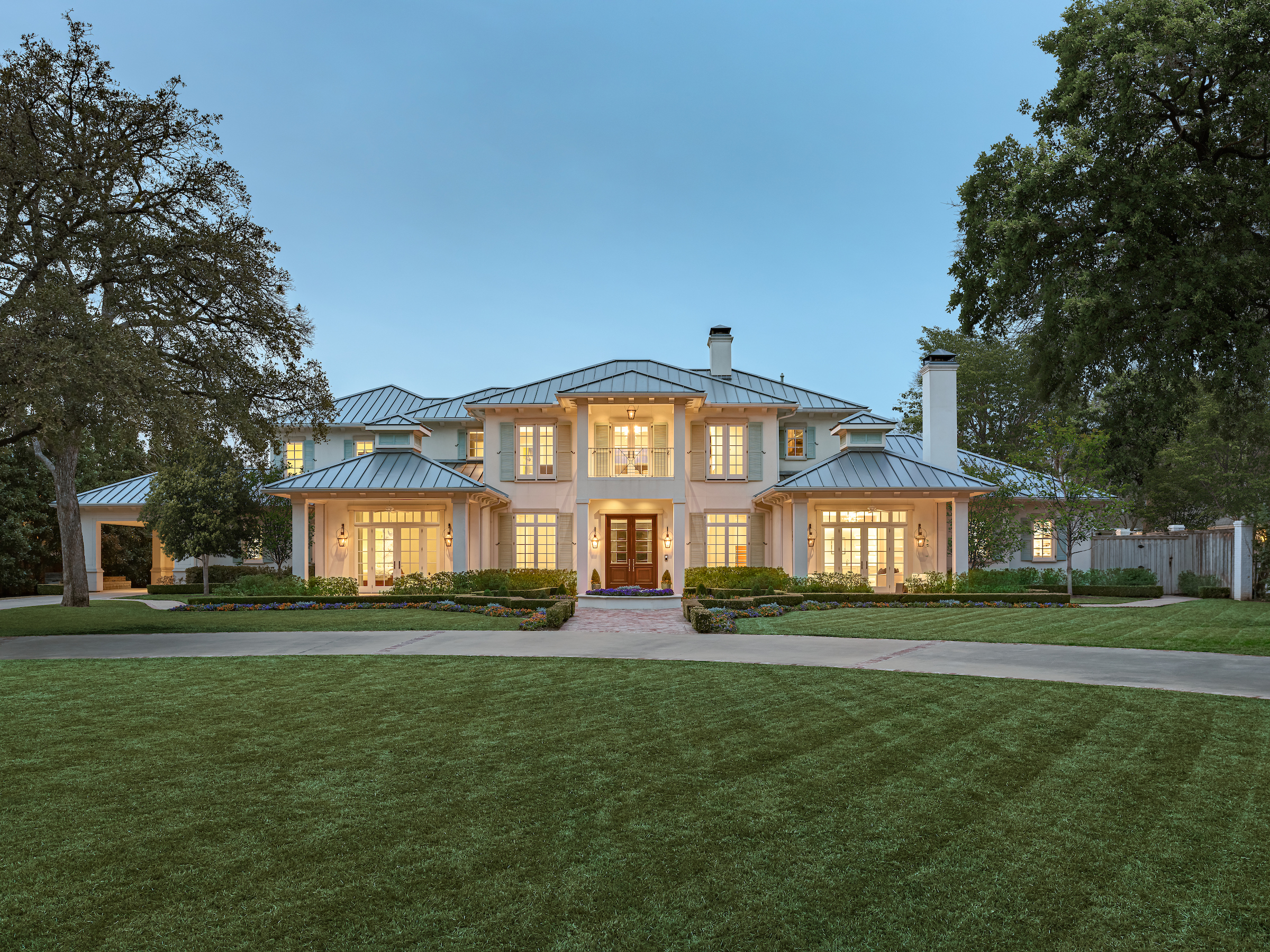 a front view of a house with a garden and trees