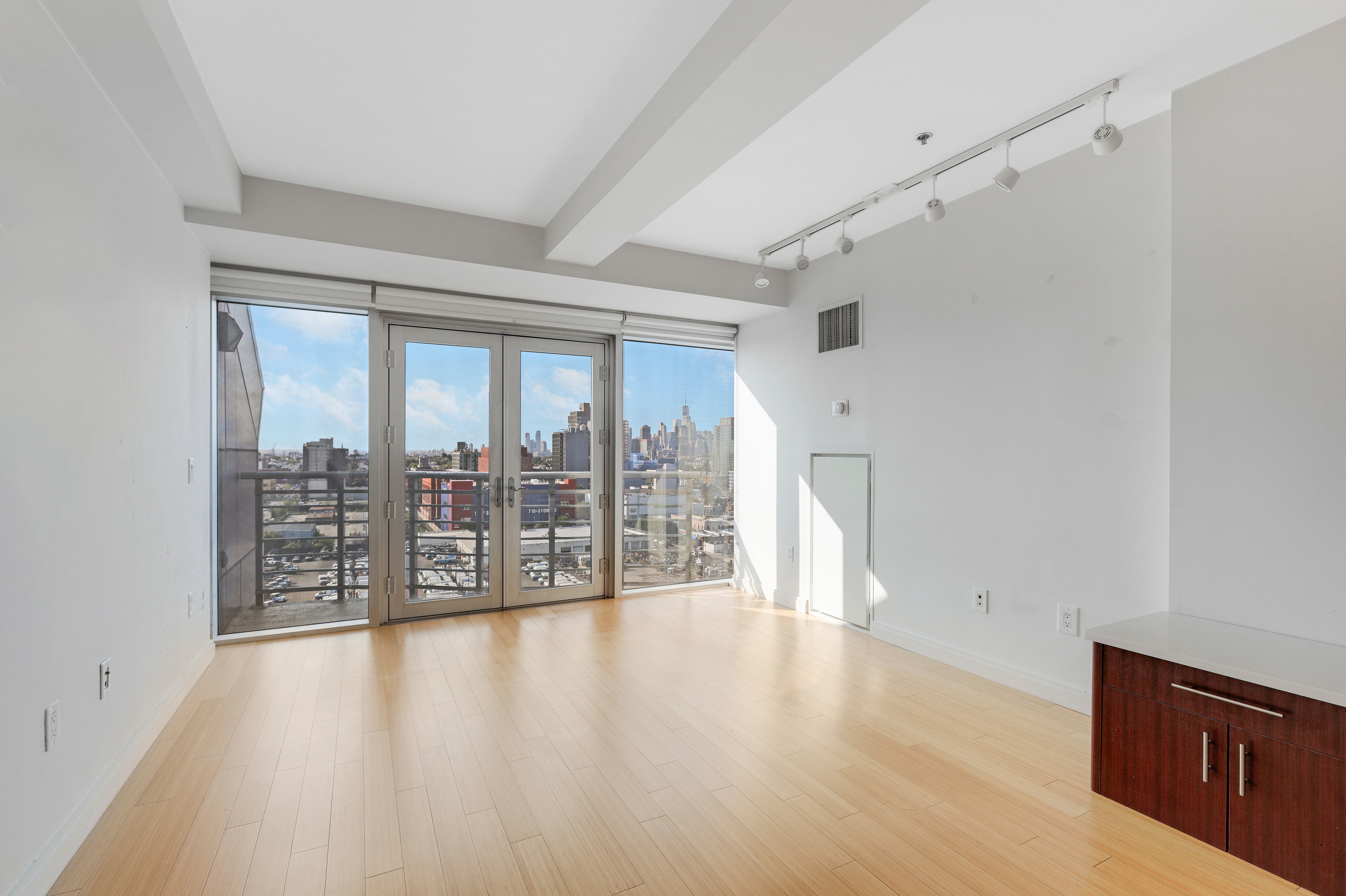 a view of an empty room with wooden floor and a window