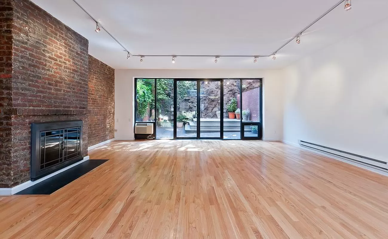 an empty room with wooden floor fireplace and windows