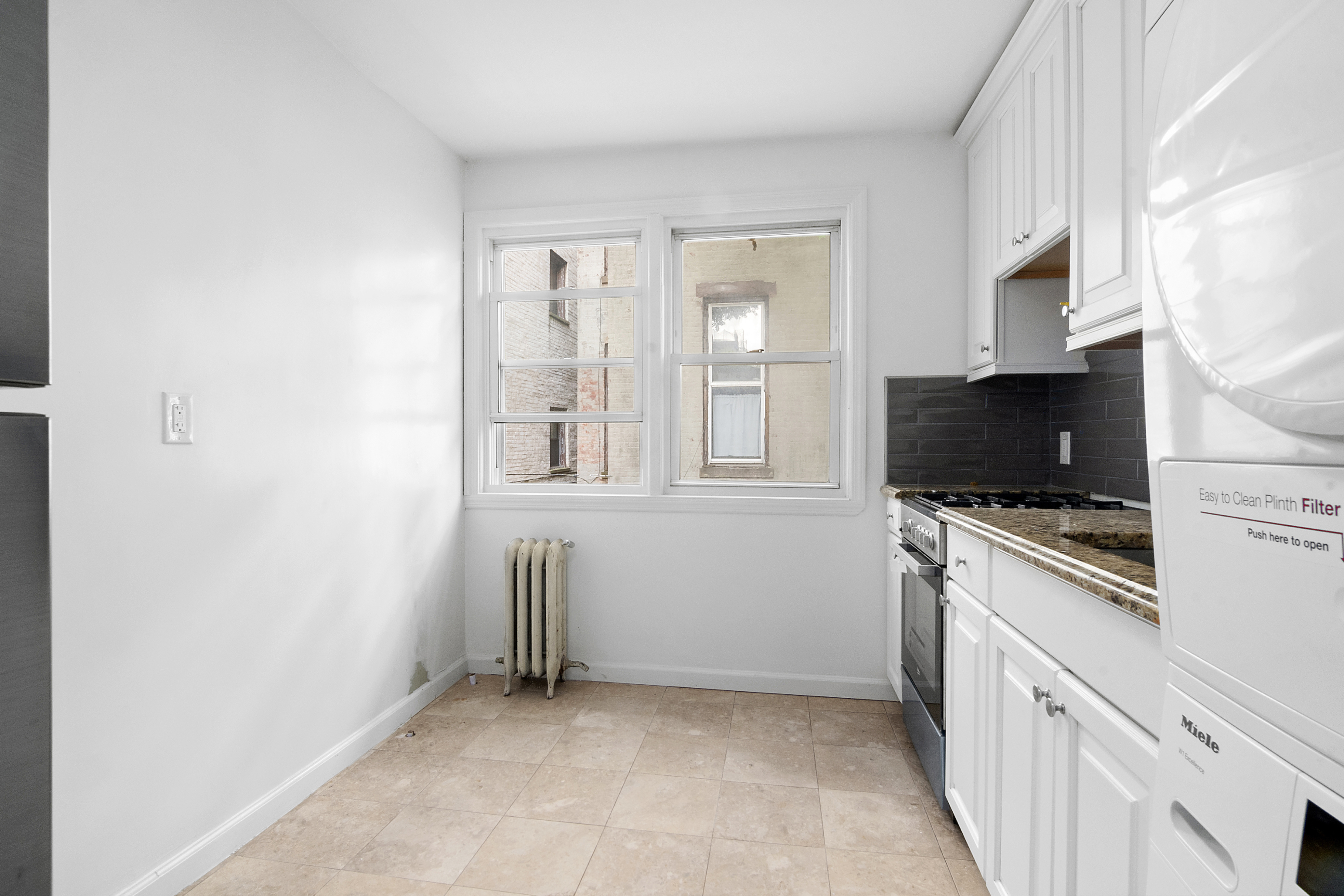 a living room with stainless steel appliances white cabinets and a flat screen tv