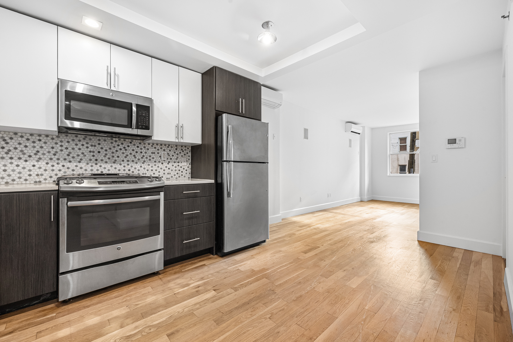 a kitchen with granite countertop wooden floors stainless steel appliances and counter space