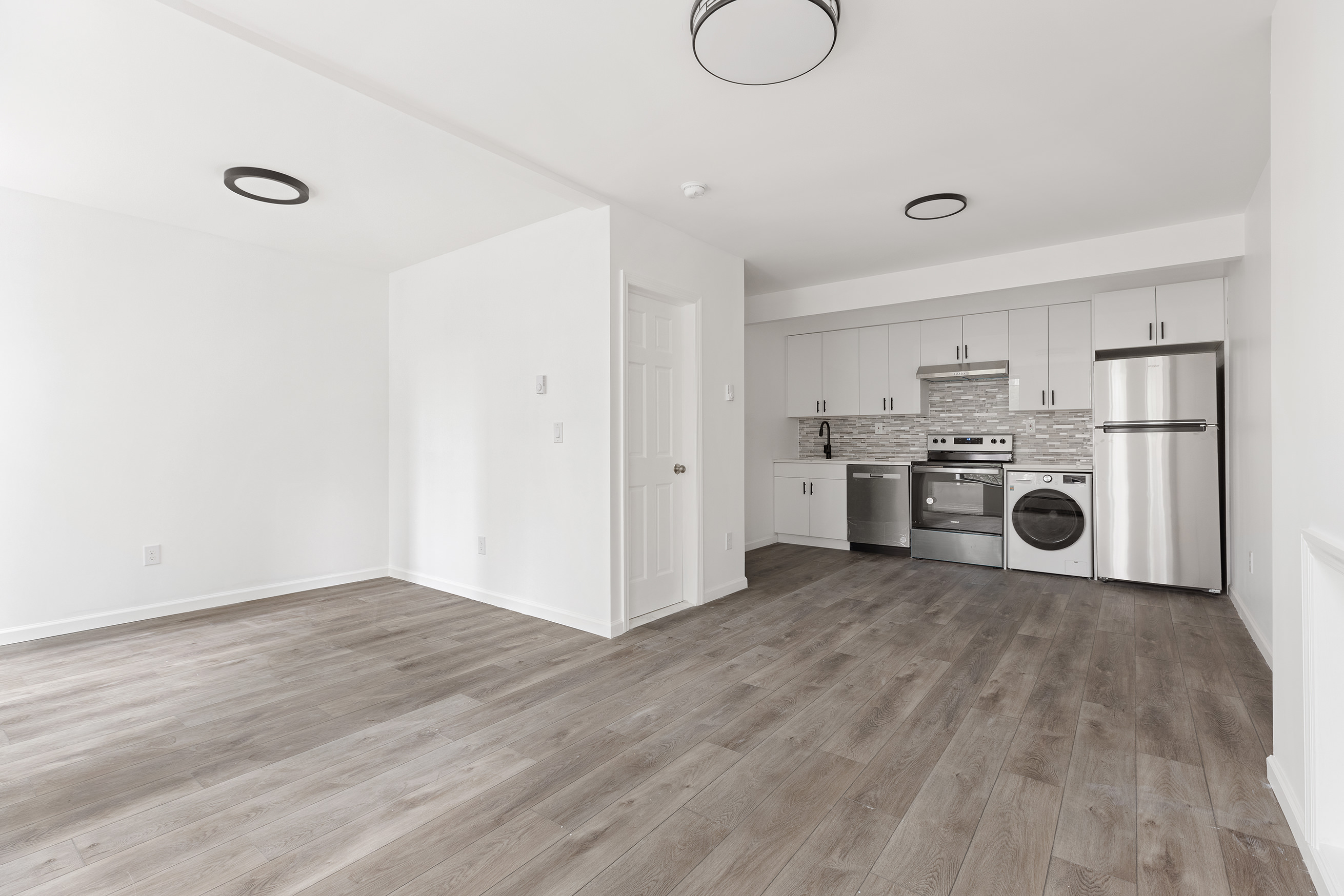 a view of a kitchen with a stove wooden cabinets and entryway