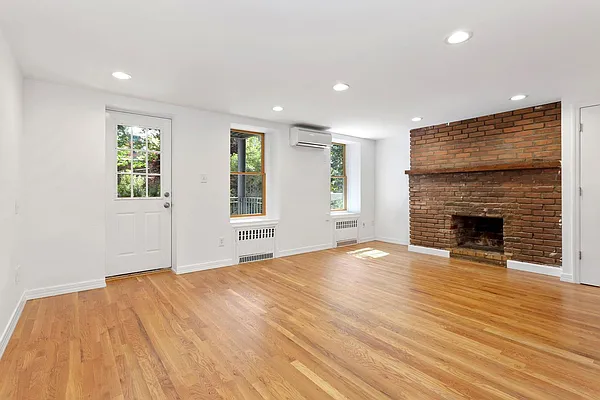 a view of empty room with wooden floor and fireplace